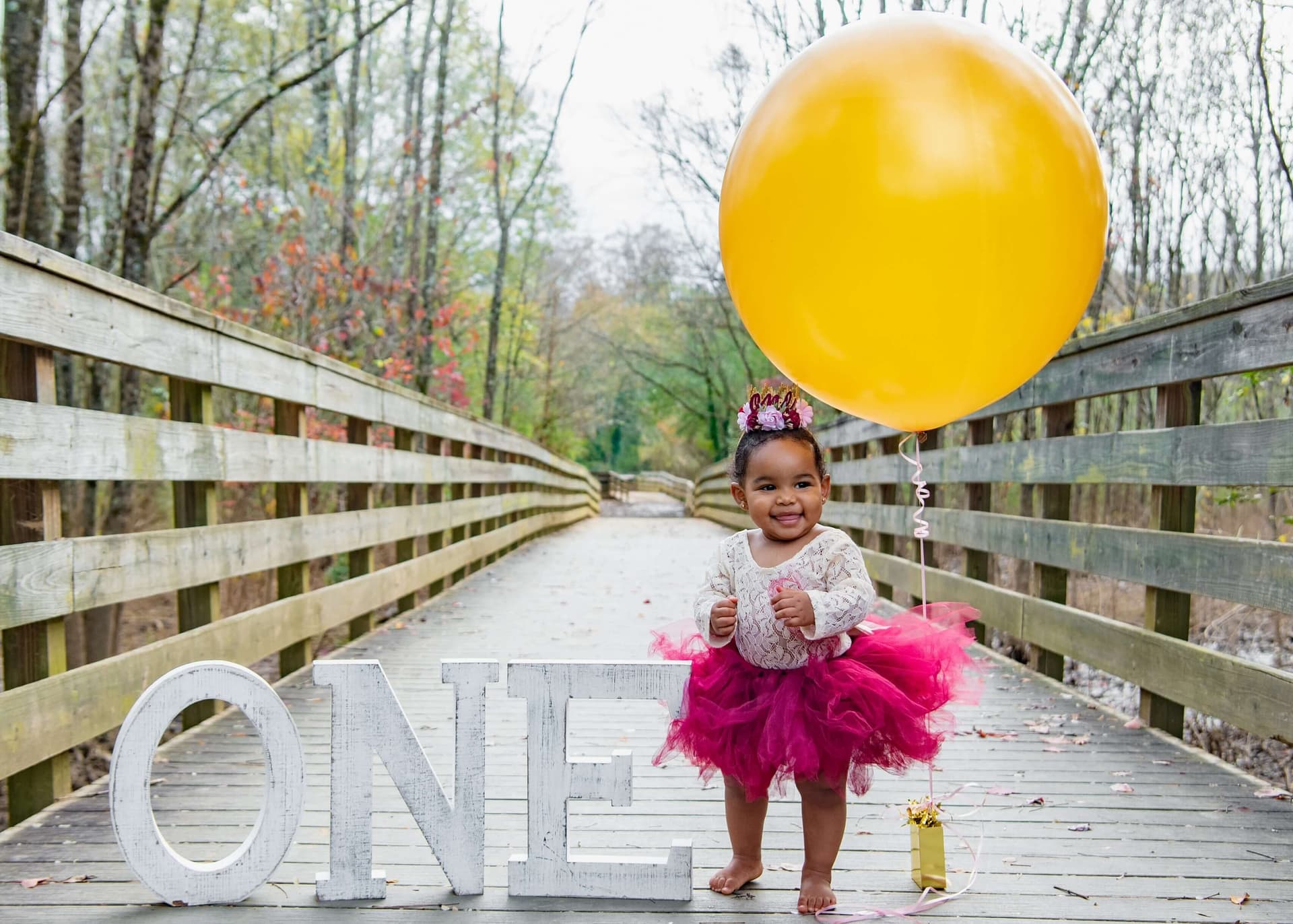 a toddler in birthday outfit with a balloon next to her