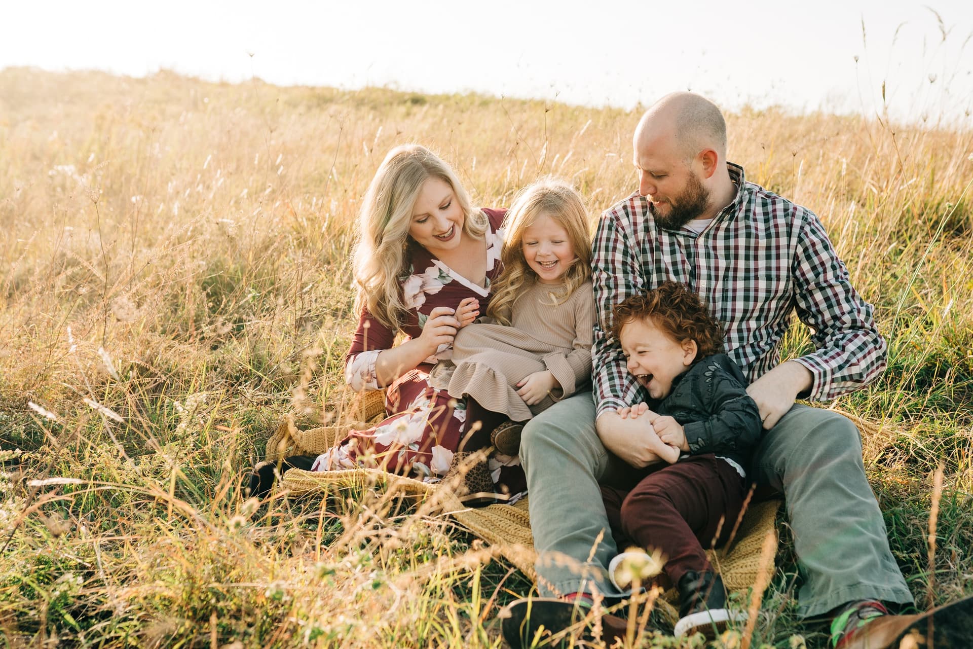 a woman in a yellow dress and a man in a suit holding each other and smiling in a field for a photoshoot