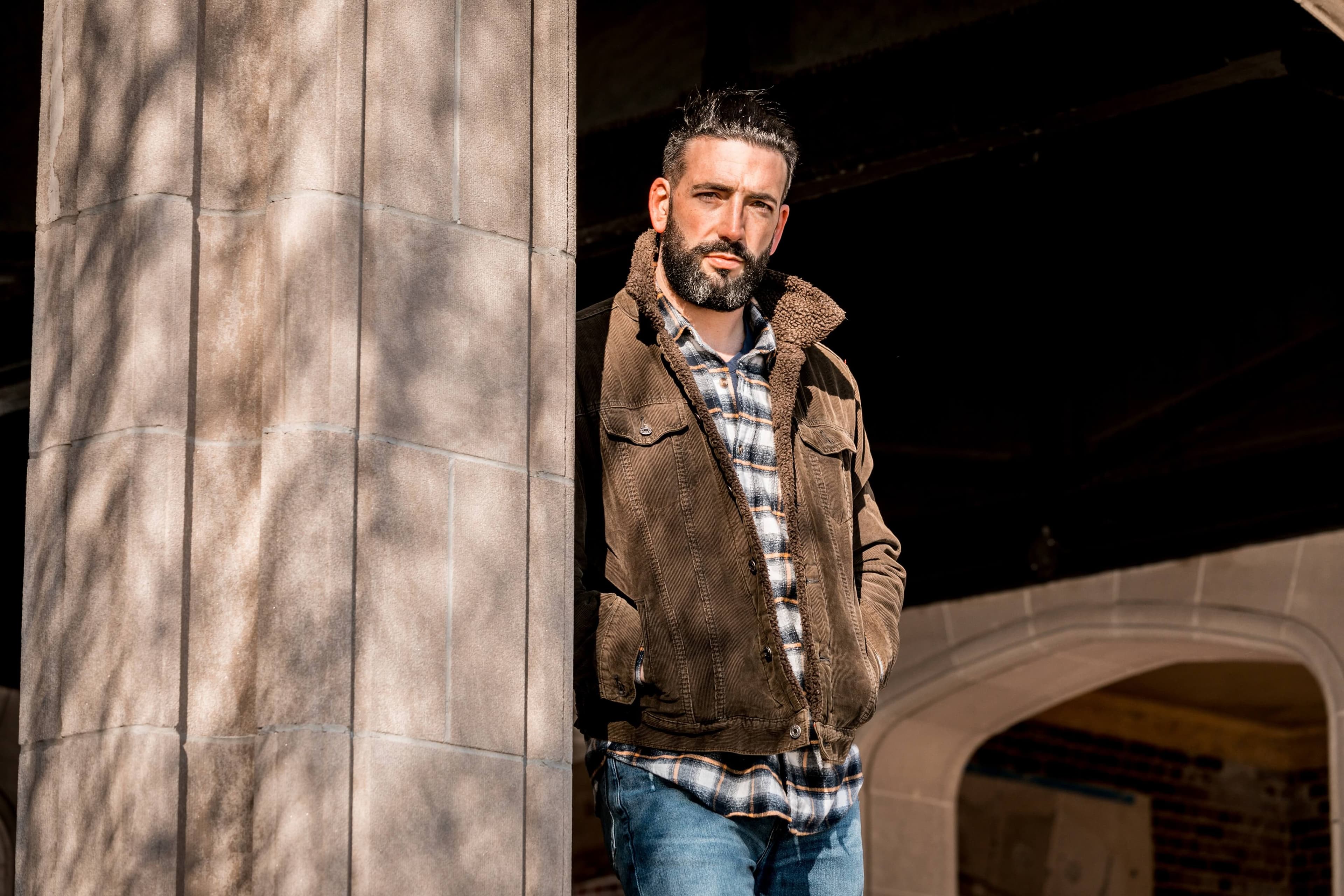 man looking out from behind a wooden wall