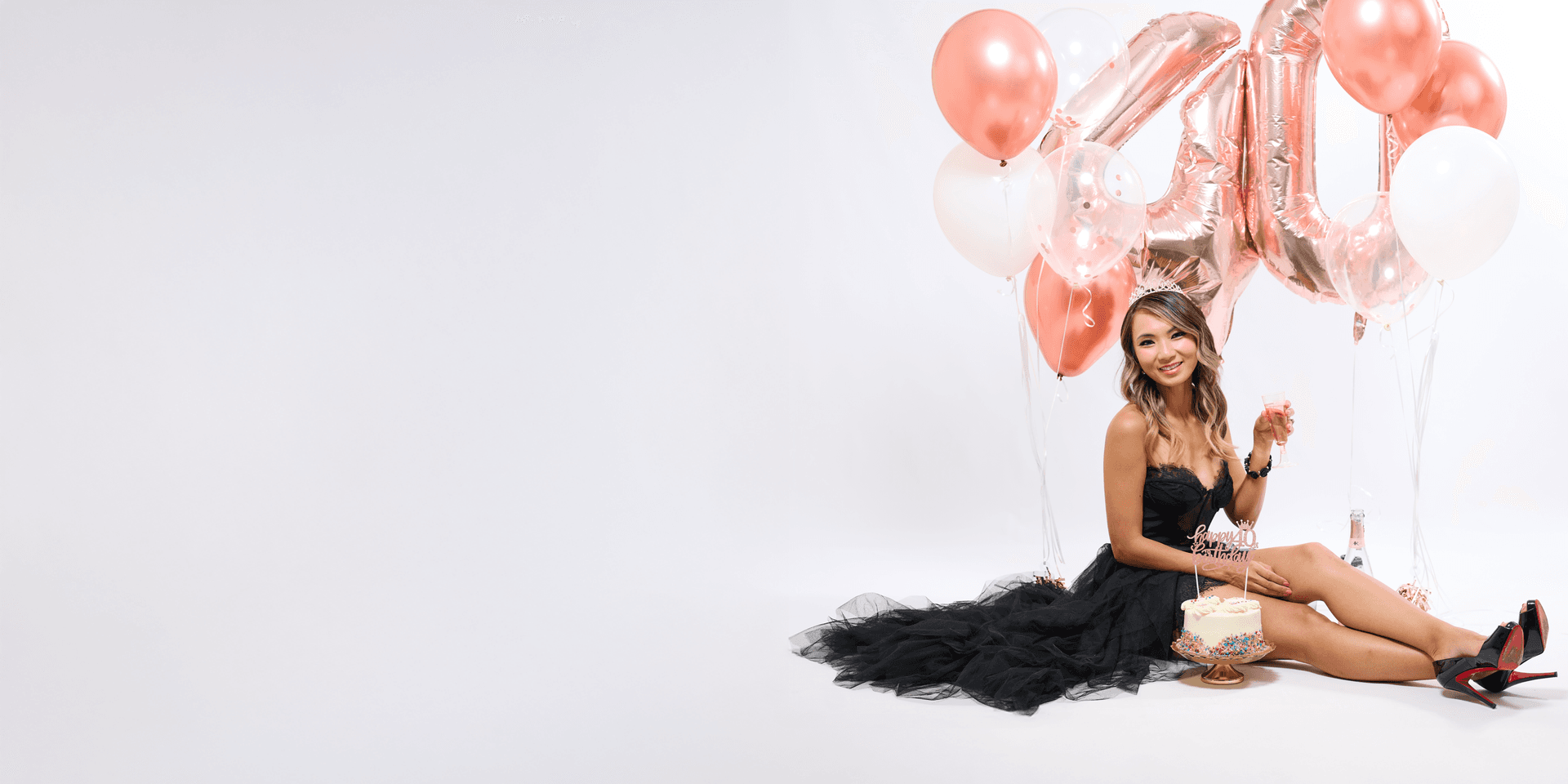 Birthday celebrant posing with balloons and a cake