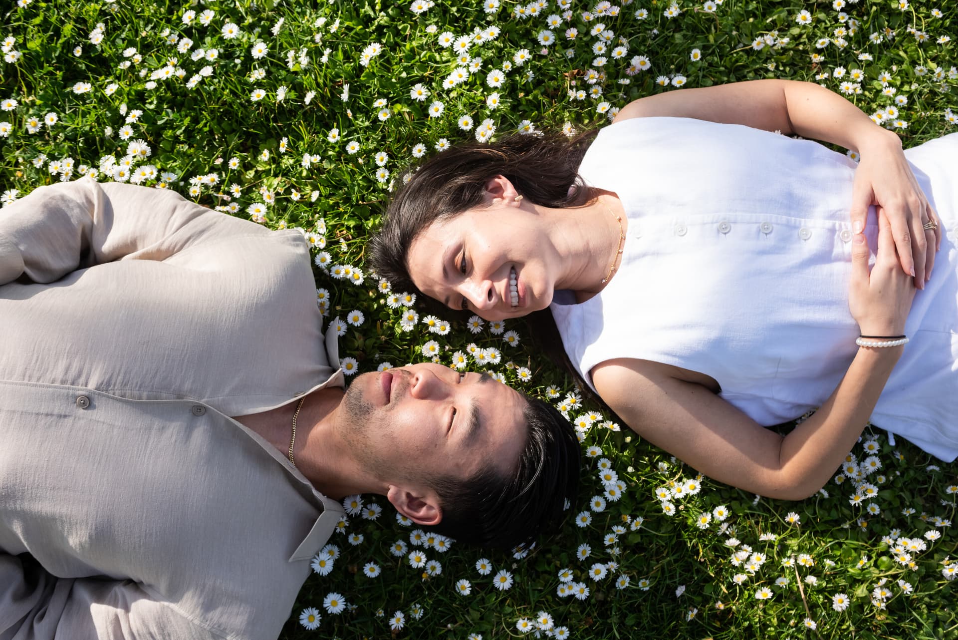 Couple lying on grass surrounded by flowers