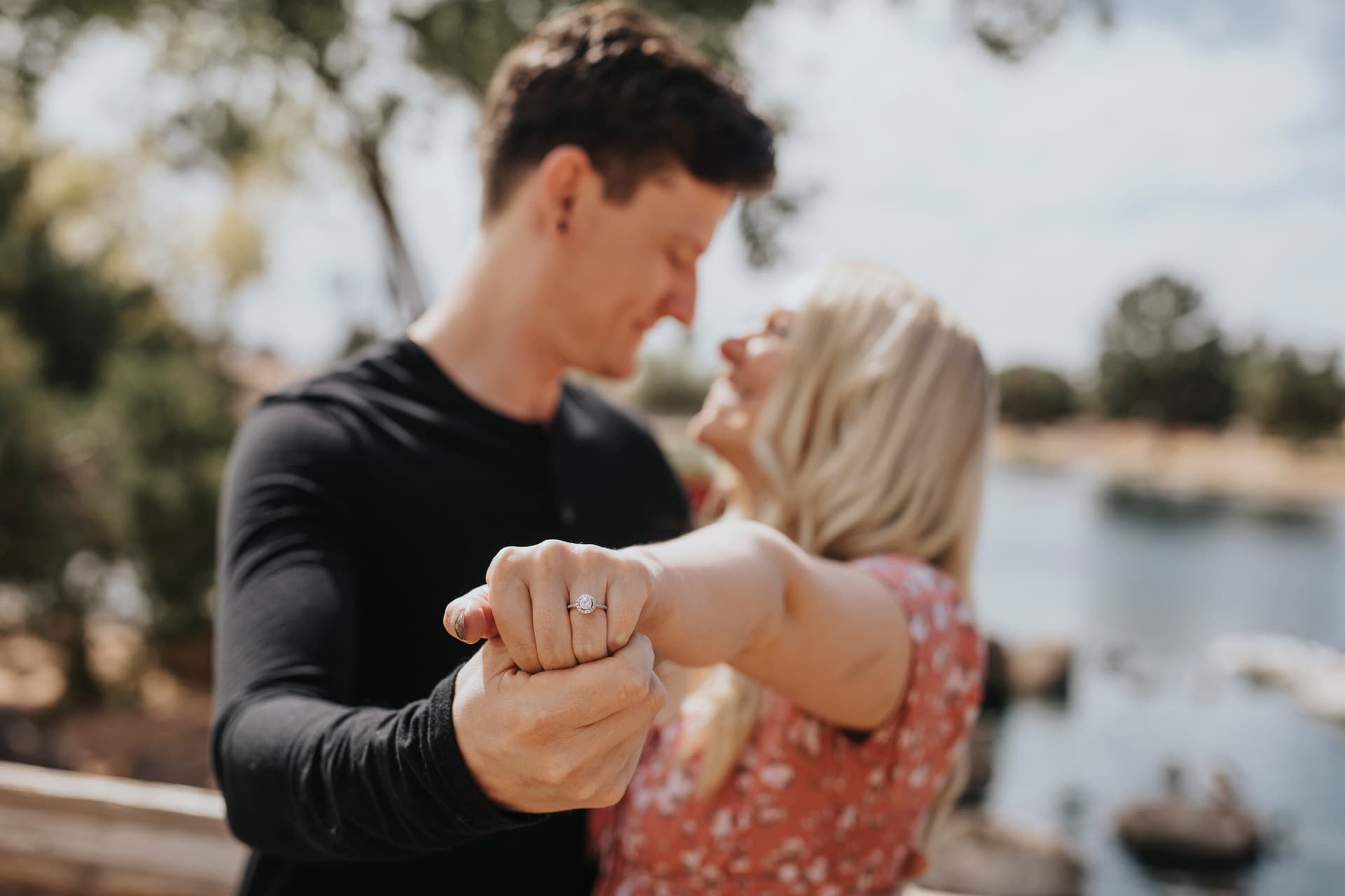 Engaged couple dancing close together outdoors with the engagement ring highlighted in the foreground