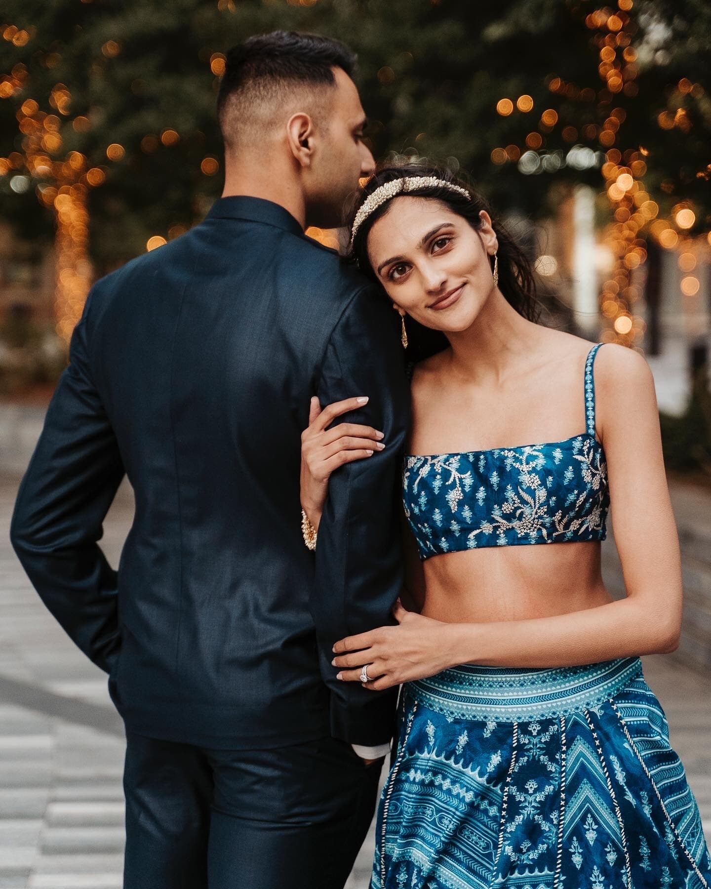 Engaged couple sharing an intimate moment with string lights glowing in the background