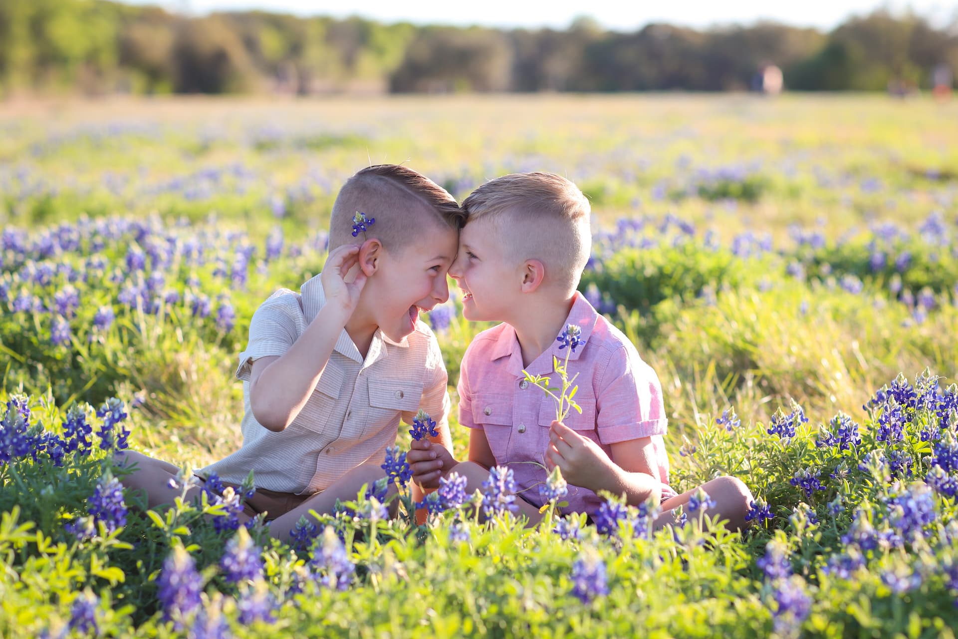 Two young siblings touching foreheads in a wildflower field