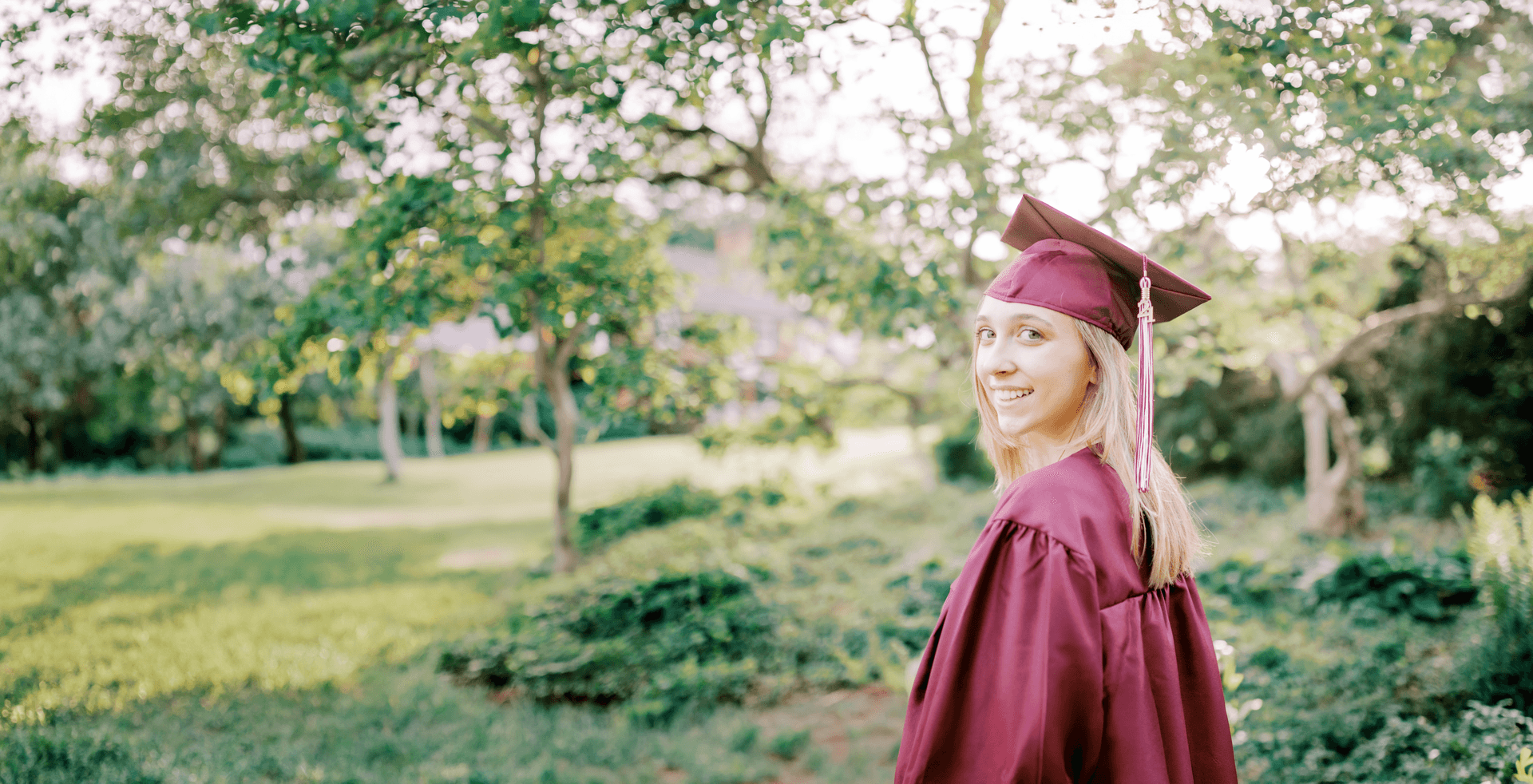 Graduate in cap and gown smiling outdoors