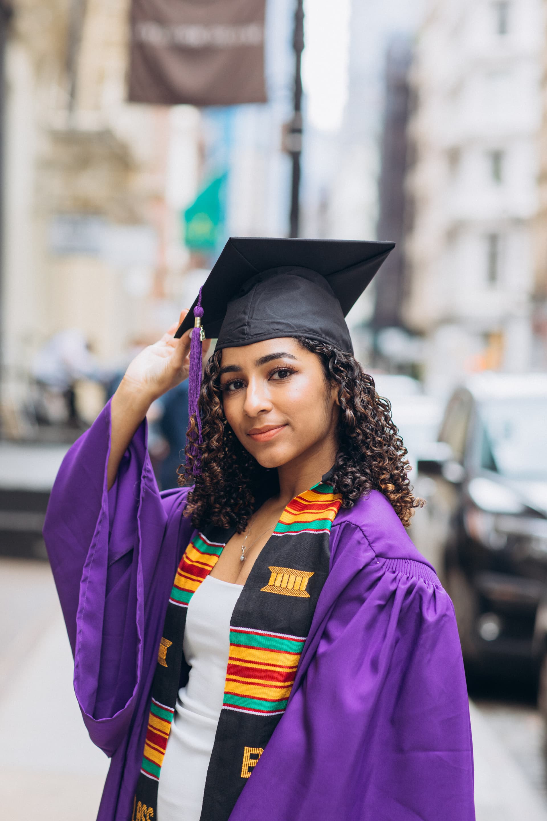Graduate wearing a cap and gown smiling at the camera