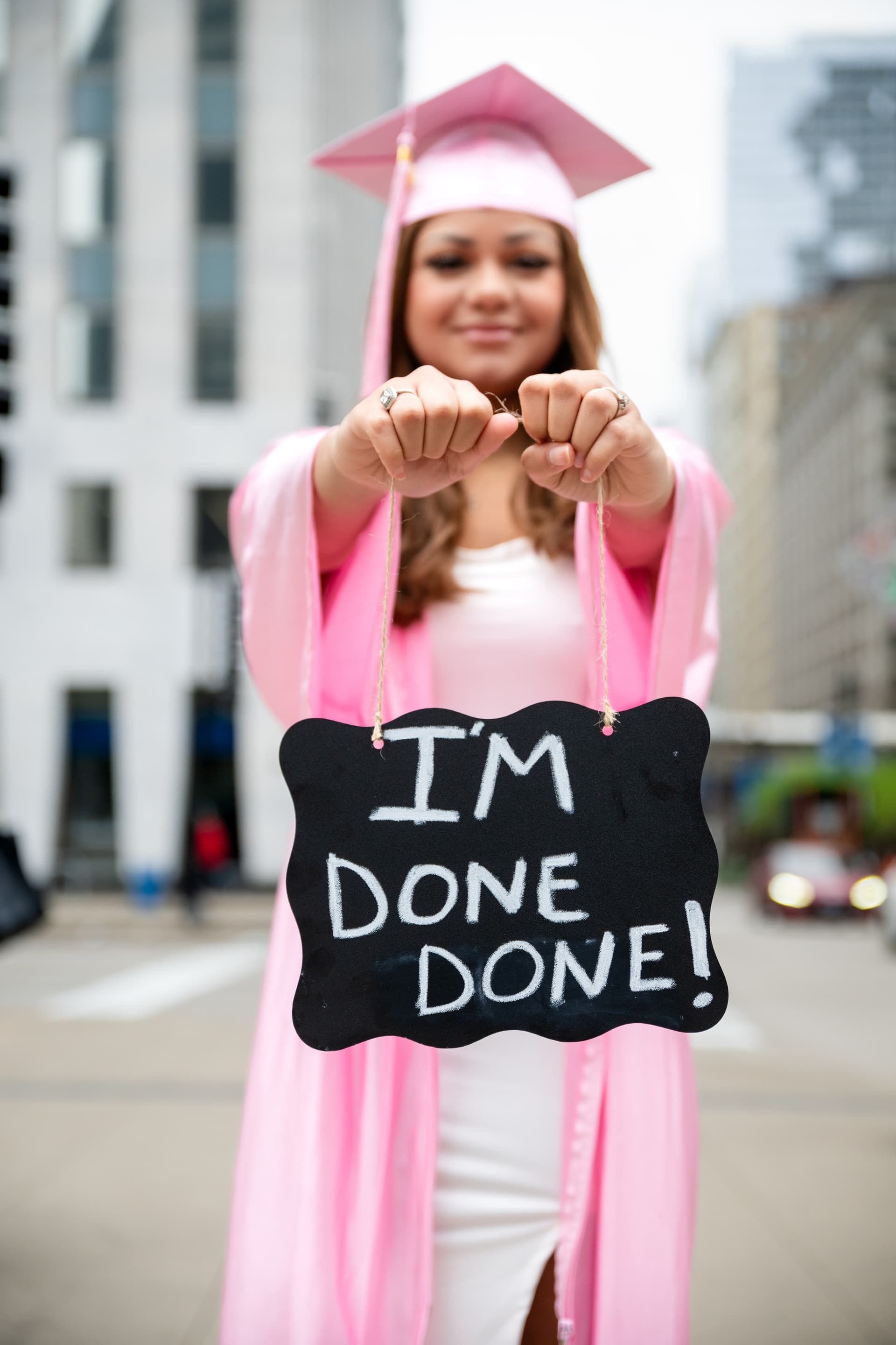 Graduate holding an "I am done" sign while smiling