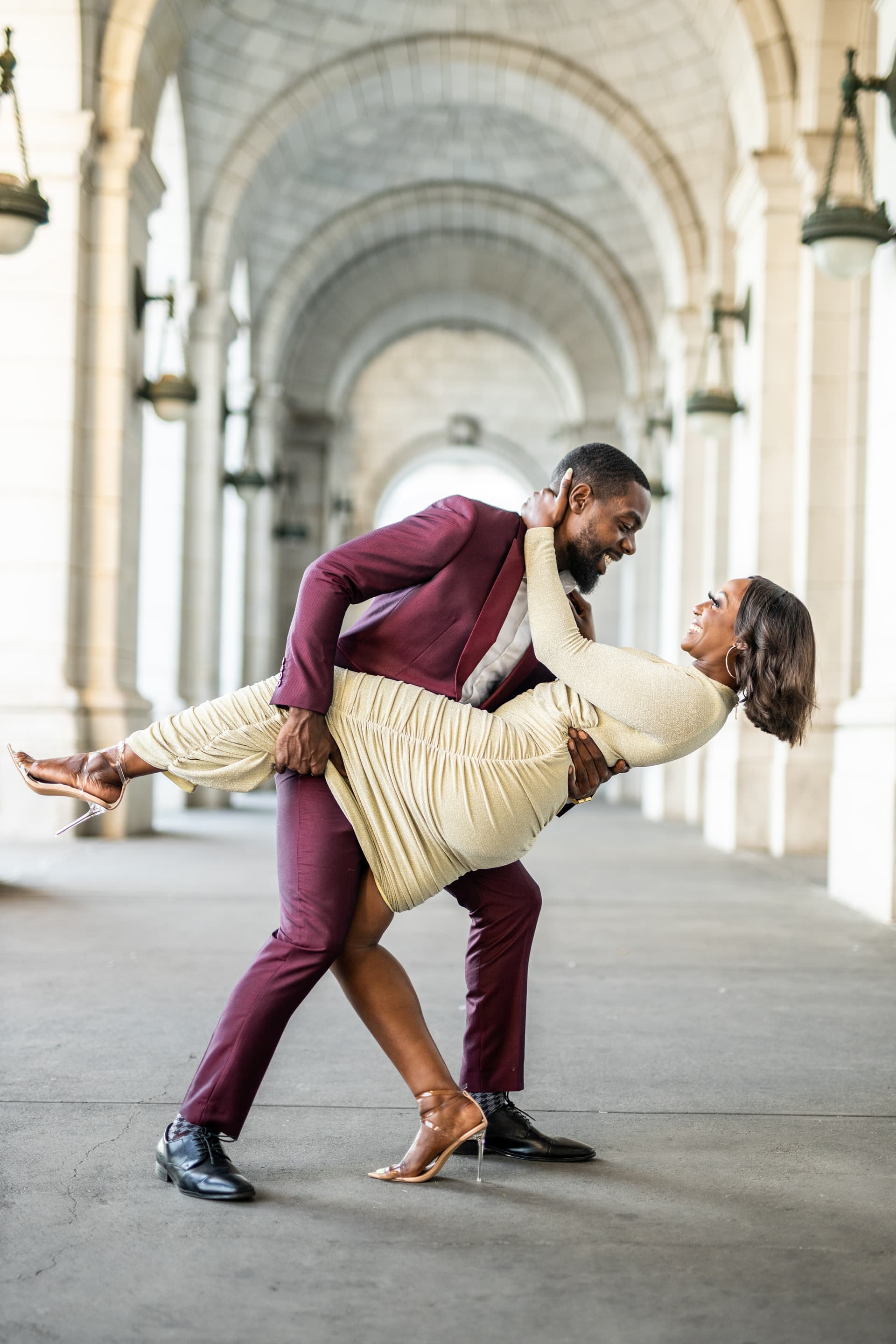 Couple in formal attire dancing in an arched indoor hallway