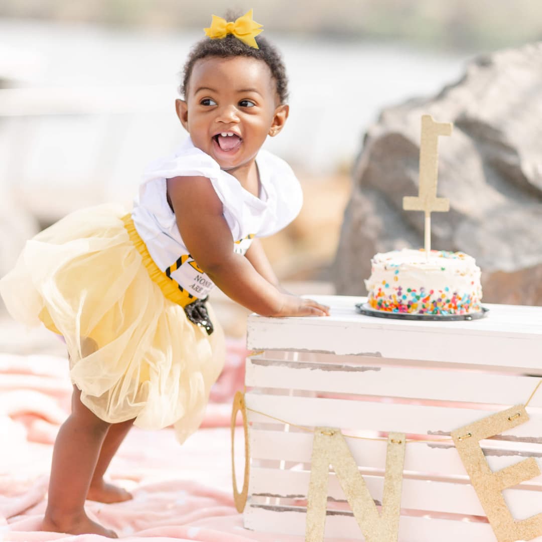 a girl standing next to a birthday cake