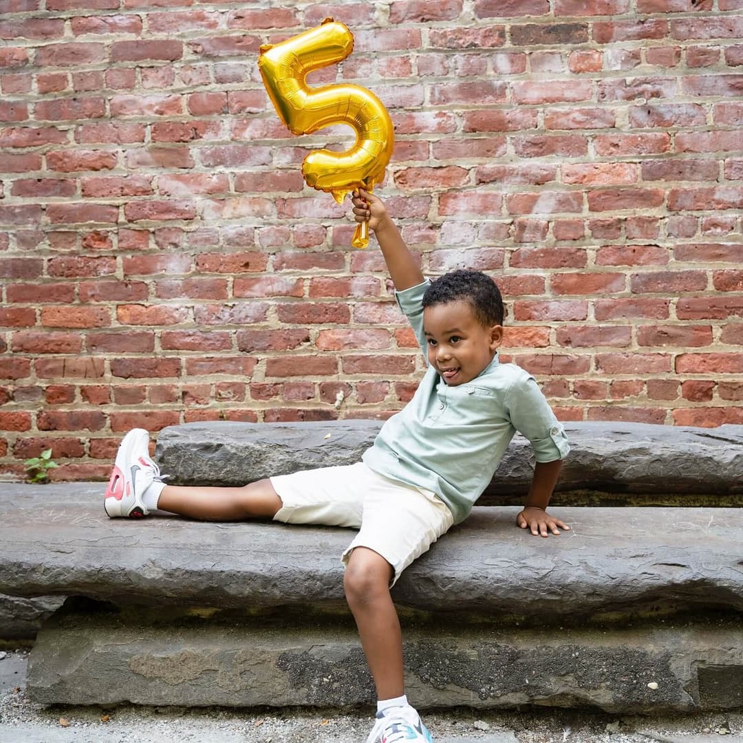 a child holding an inflatable number 5