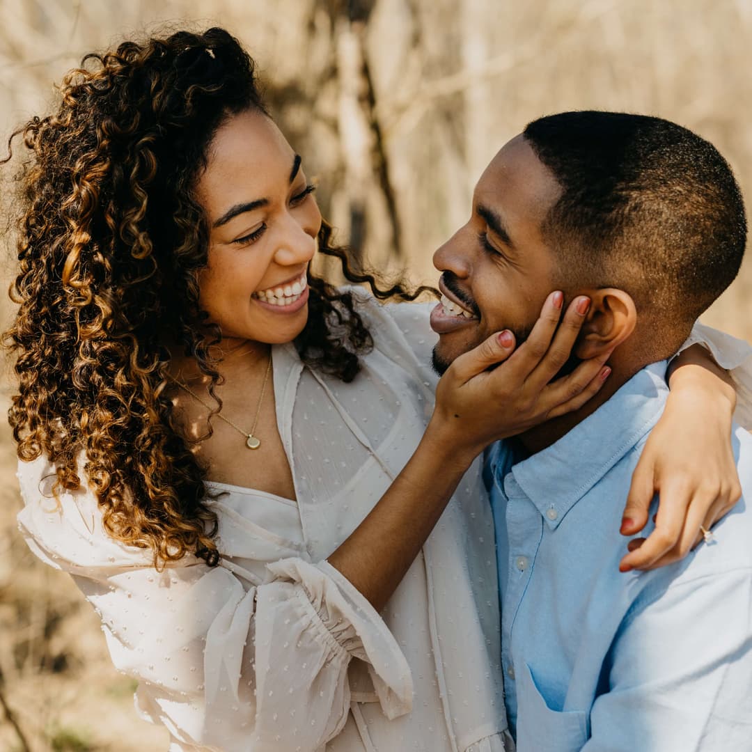 two people smiling in a forest