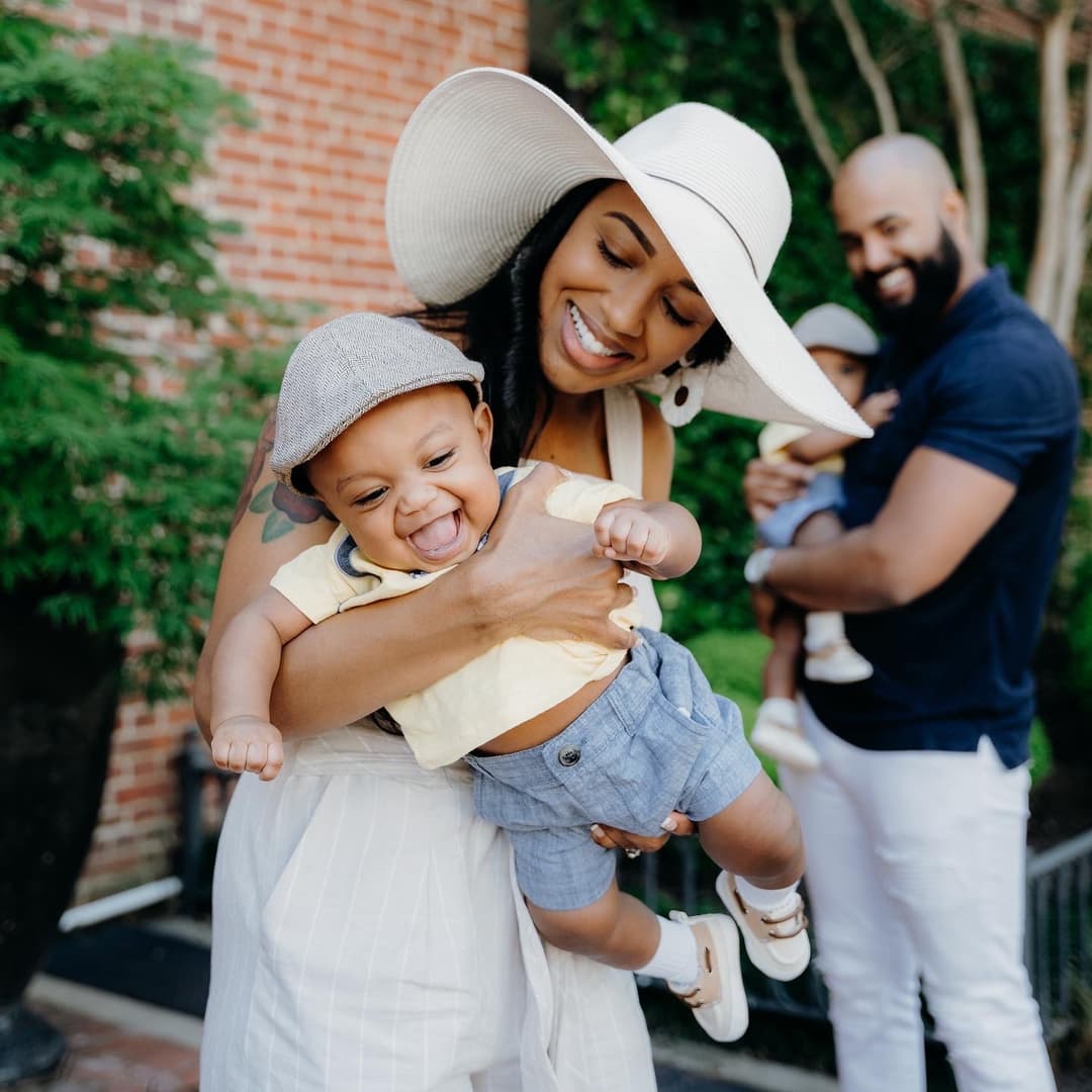 happy family holding up two children next to their house