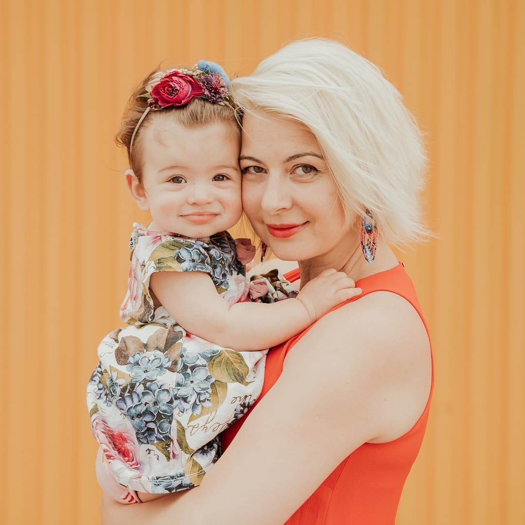 mother holding a baby in front of a fabric background
