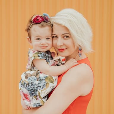 mother holding a baby in front of a fabric background
