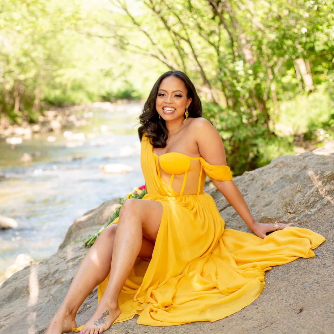 woman in yellow outfit sitting in front of a river