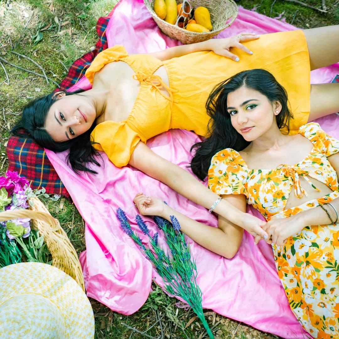 two women laying down on a picnic blanket 