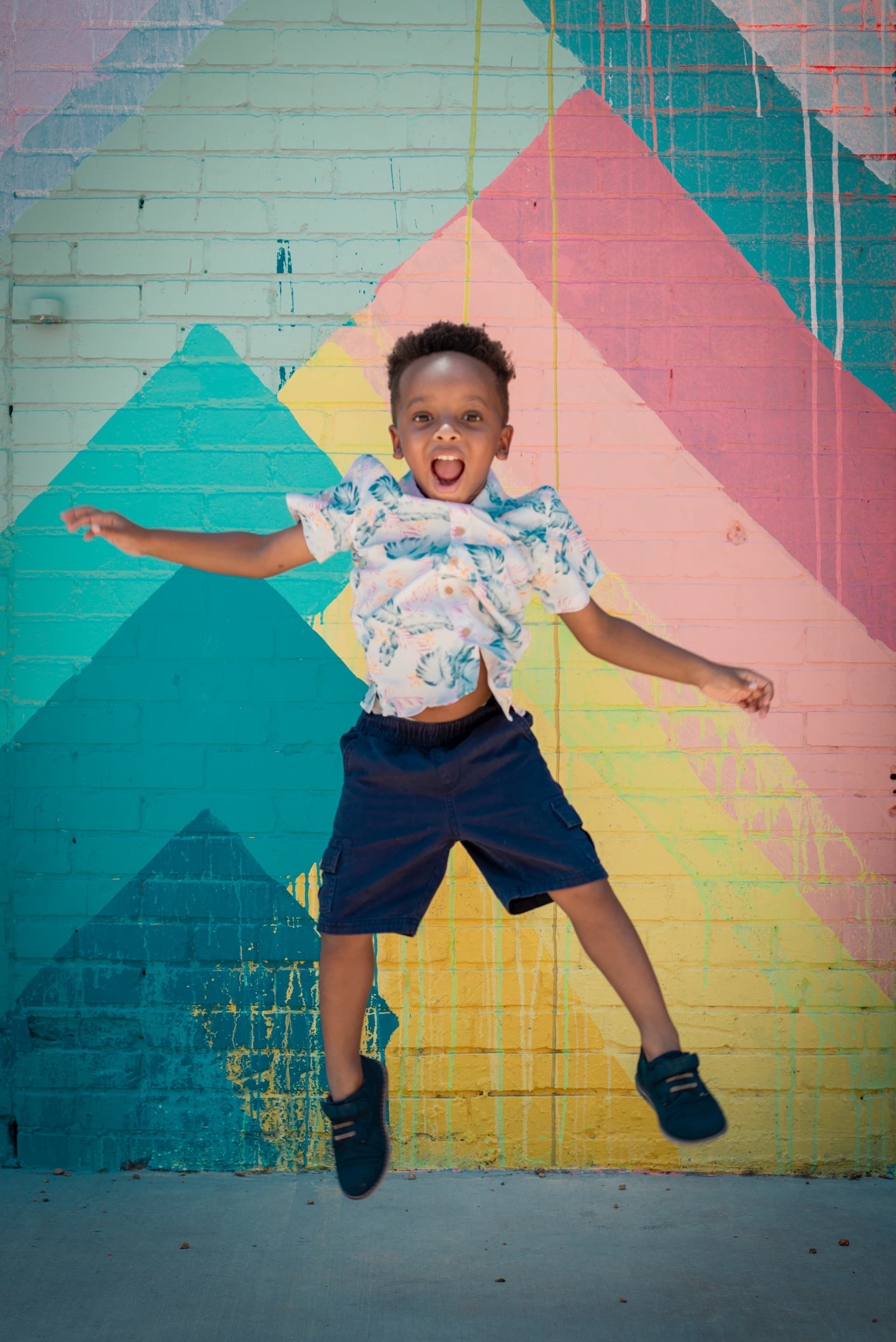 Boy jumping in front of colorful mural
