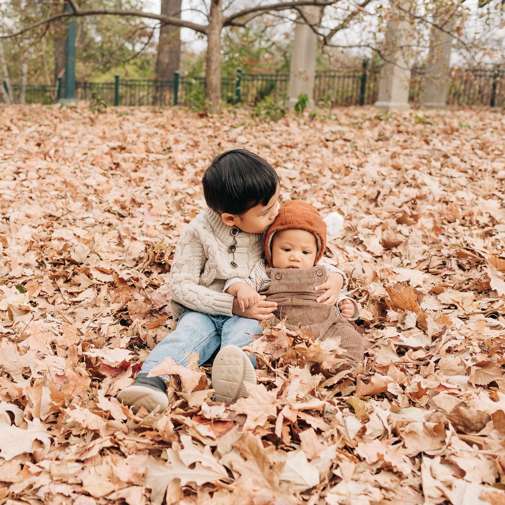 Siblings sit in leaves for a free outdoor fall photoshoot