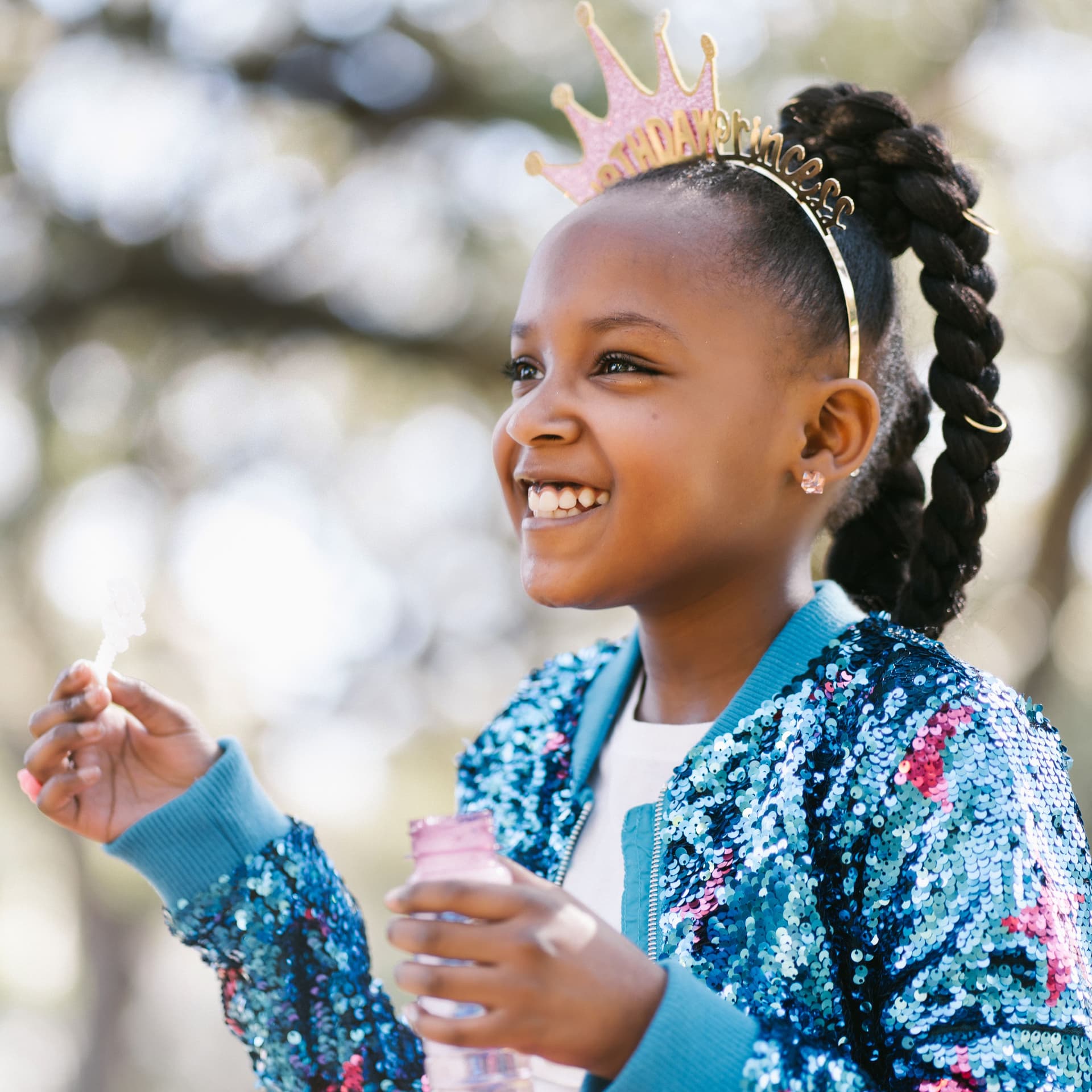 Smiling girl wearing a birthday crown poses for her free outdoor birthday photoshoot