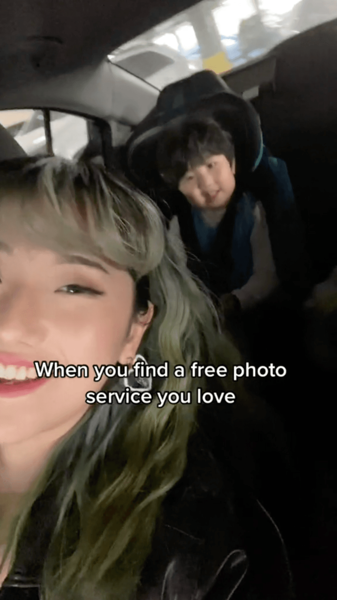 A selfie of a smiling person in the front seat with another person in the backseat of a car, with text overlay about a free photo service.