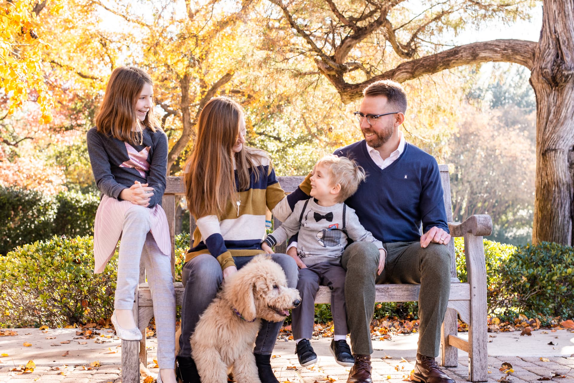 family with a dog sitting on a bench posing for a photoshoot