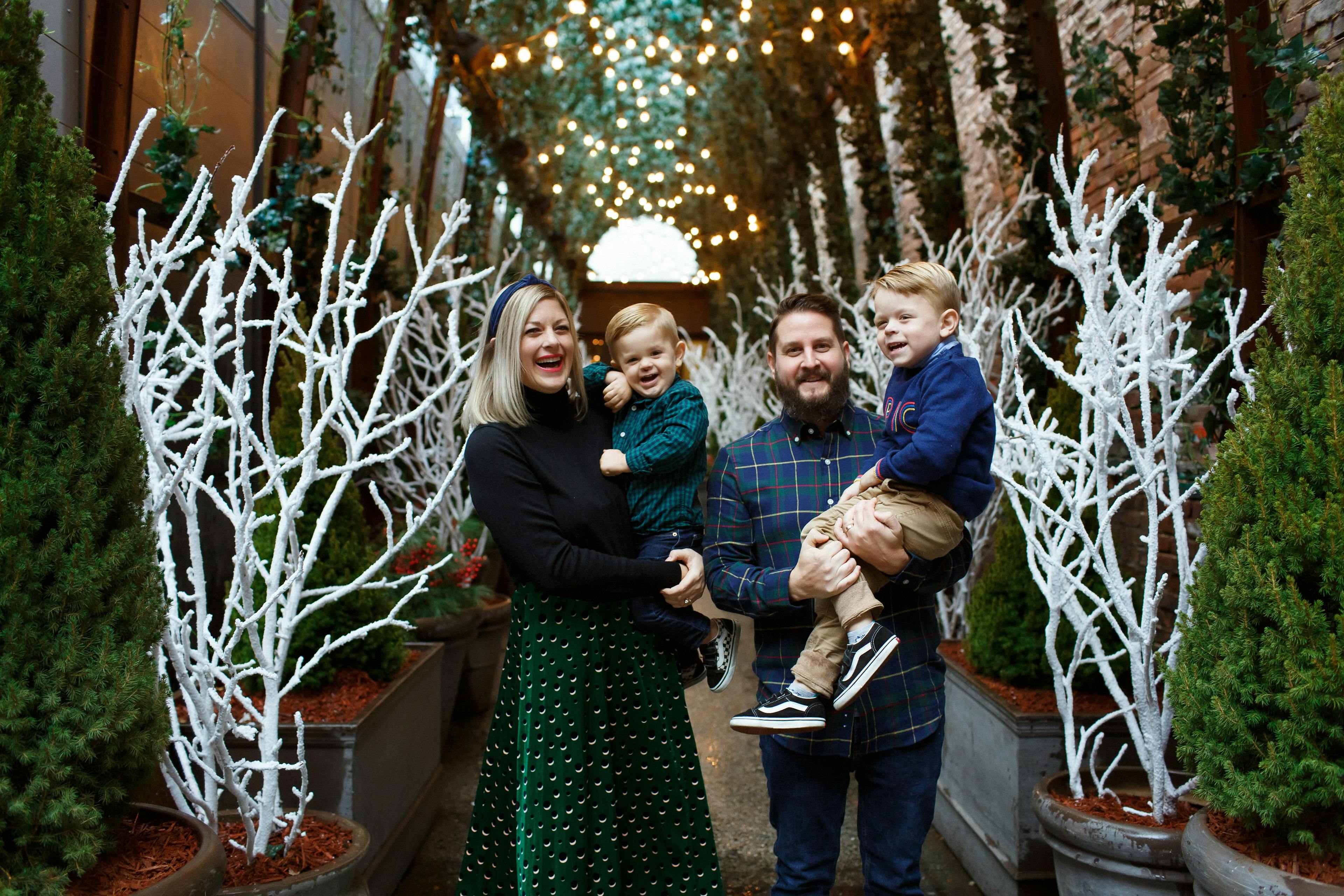 family with two kids standing under christmas decorations