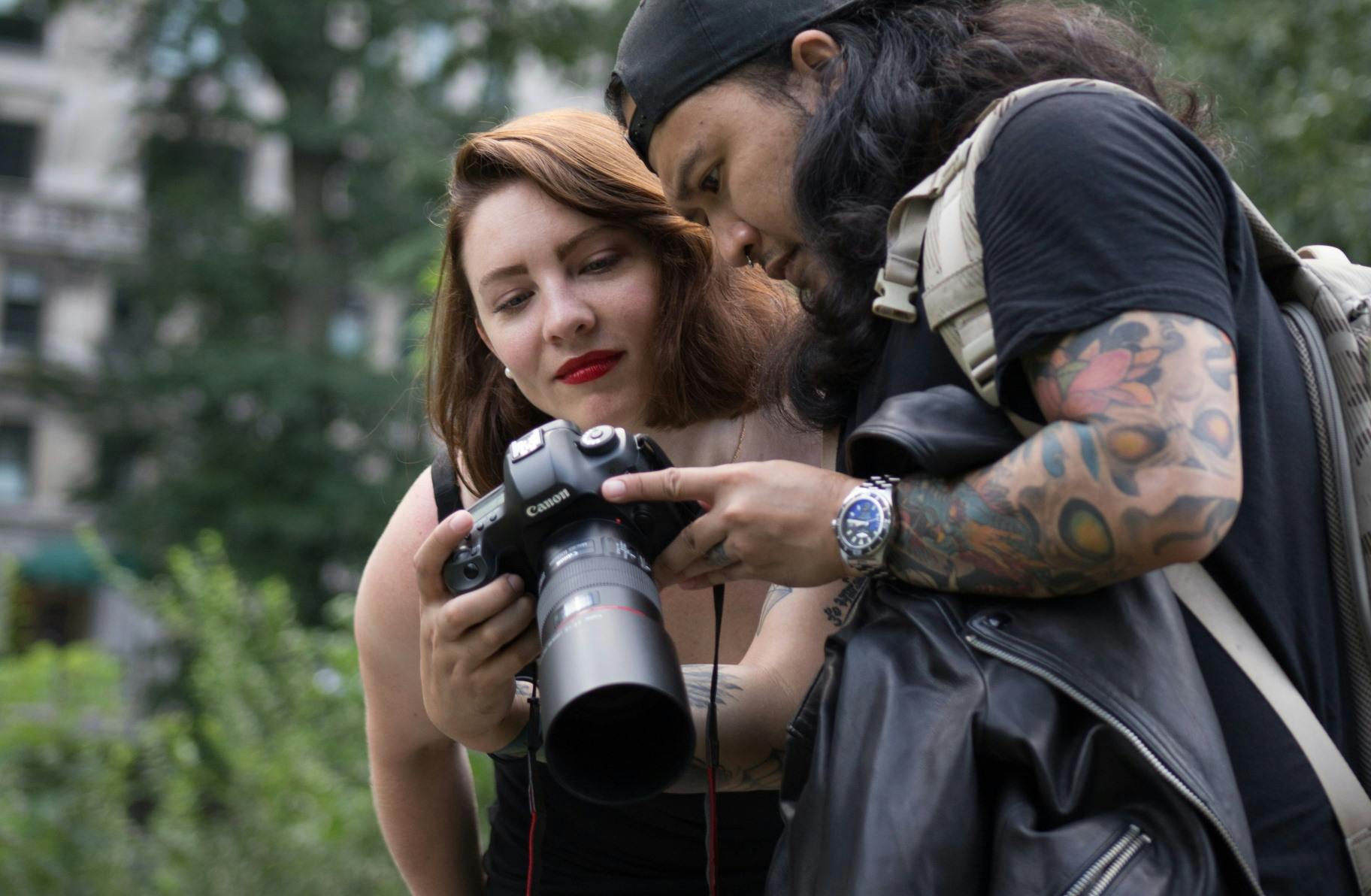 man and woman inspect photos during their free outdoor photoshoot