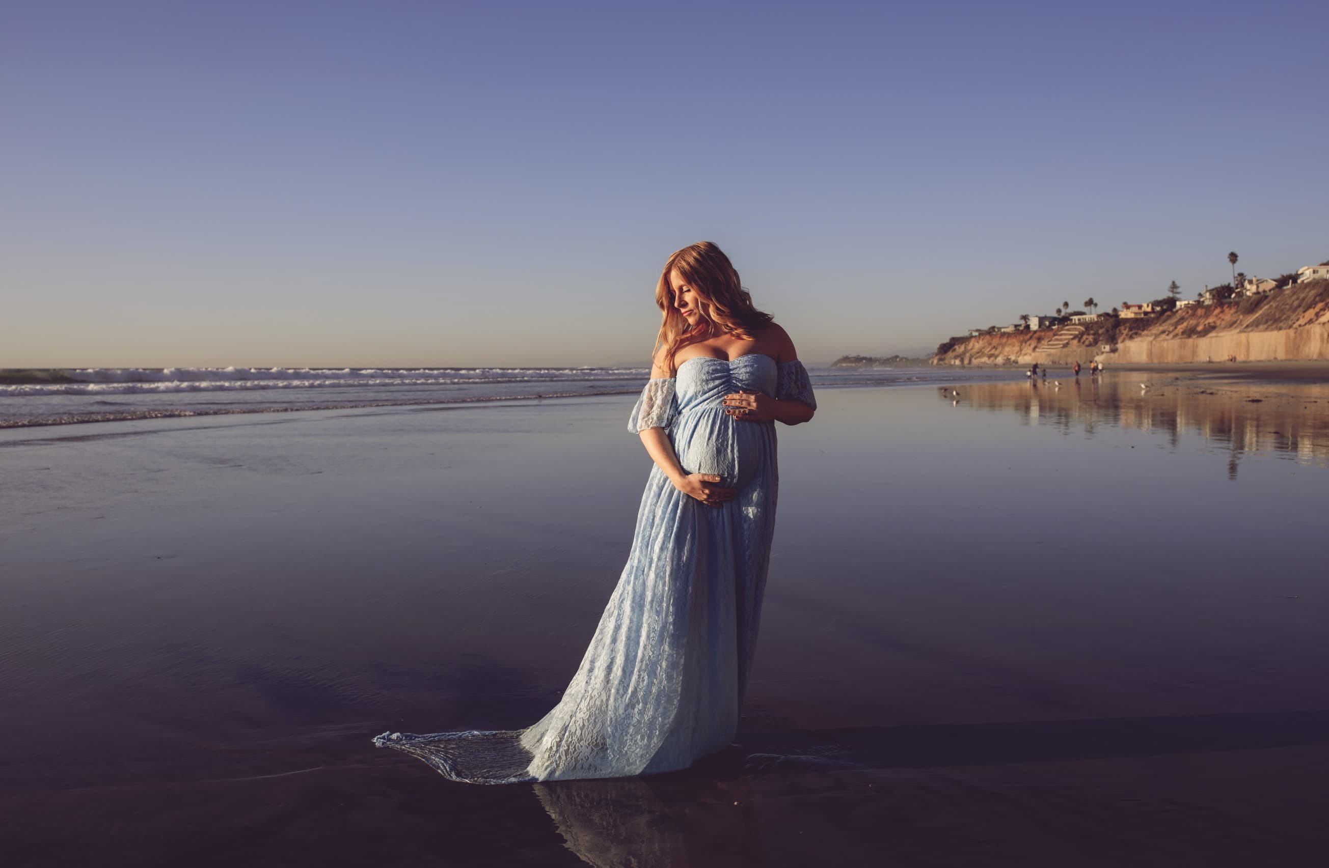 a pregnant woman on a beach in shallow water