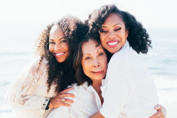 Three women in front of an ocean.