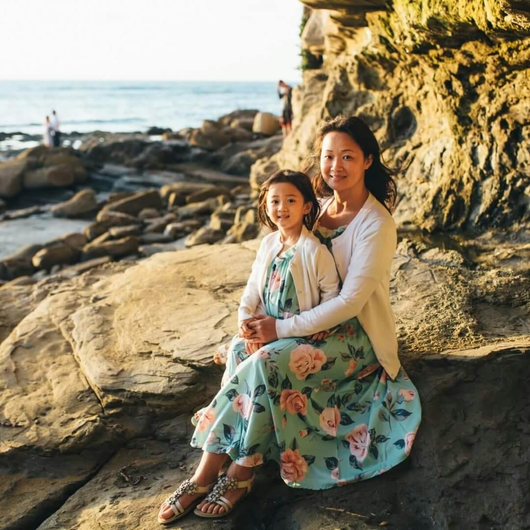 a woman and her child on a rocky coast.