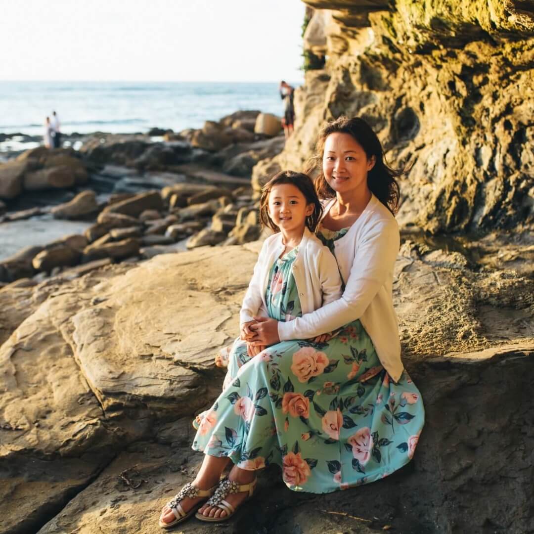 a woman and her child on a rocky coast.