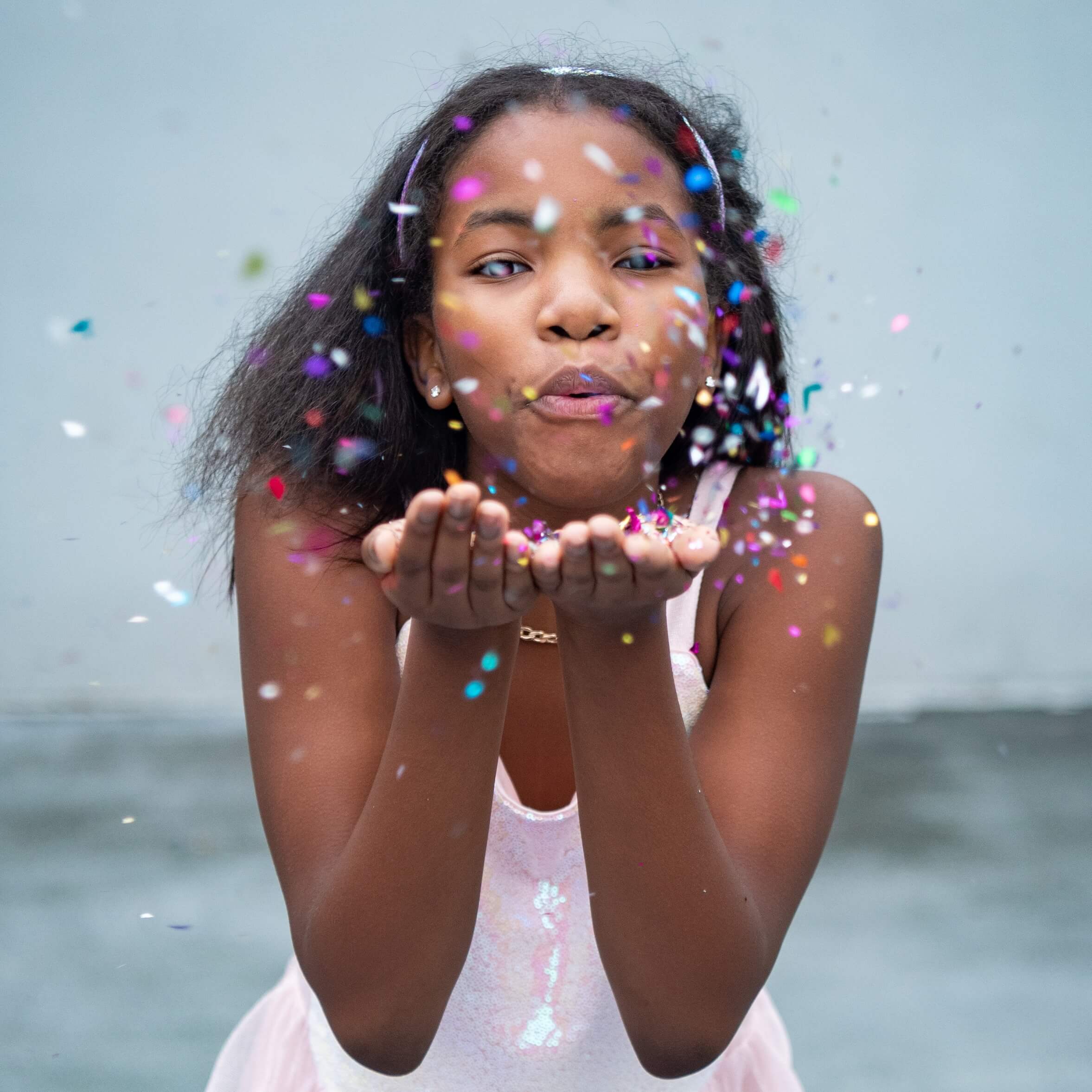 a woman blowing confetti on a beach.