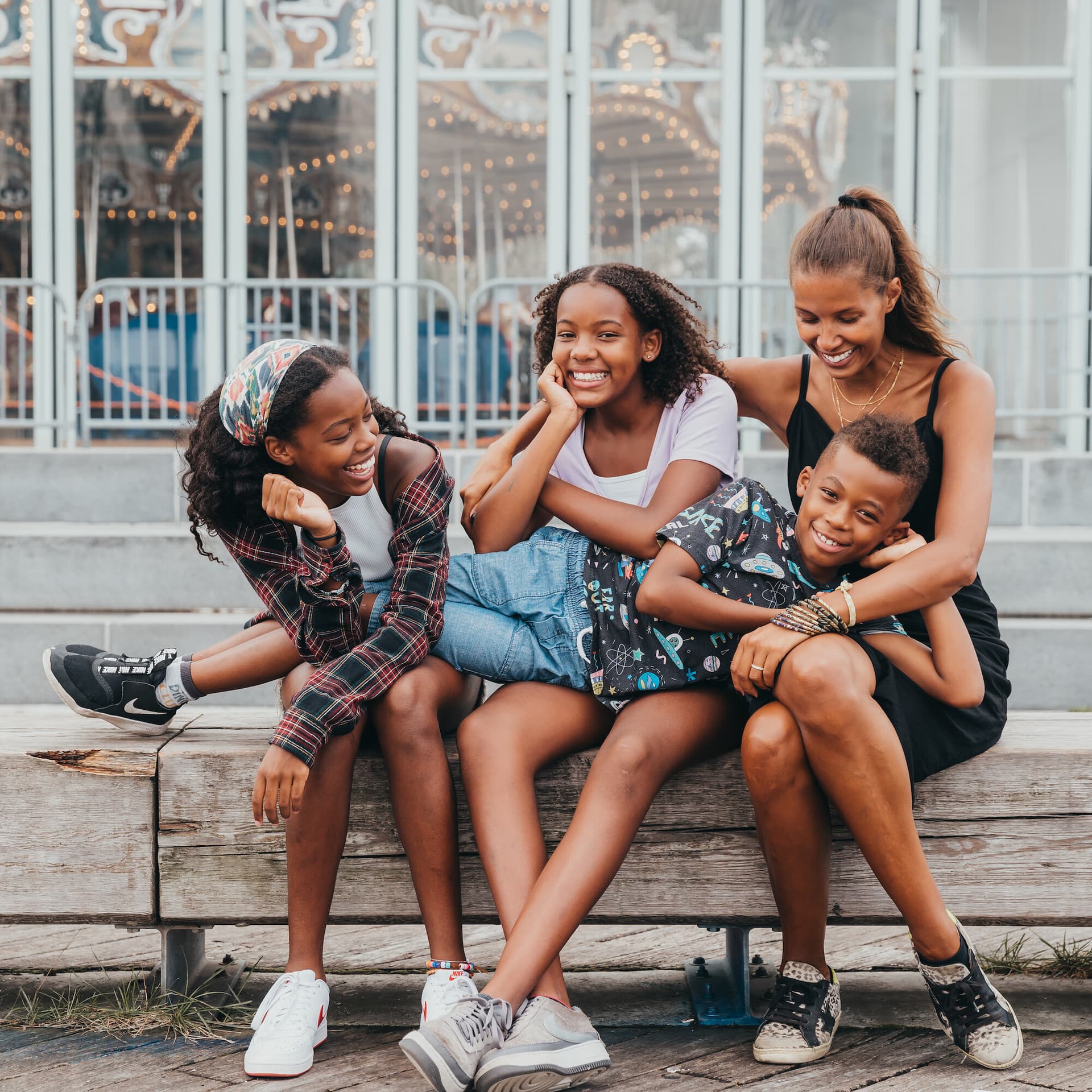 Mother sitting on steps with three children smiling together
