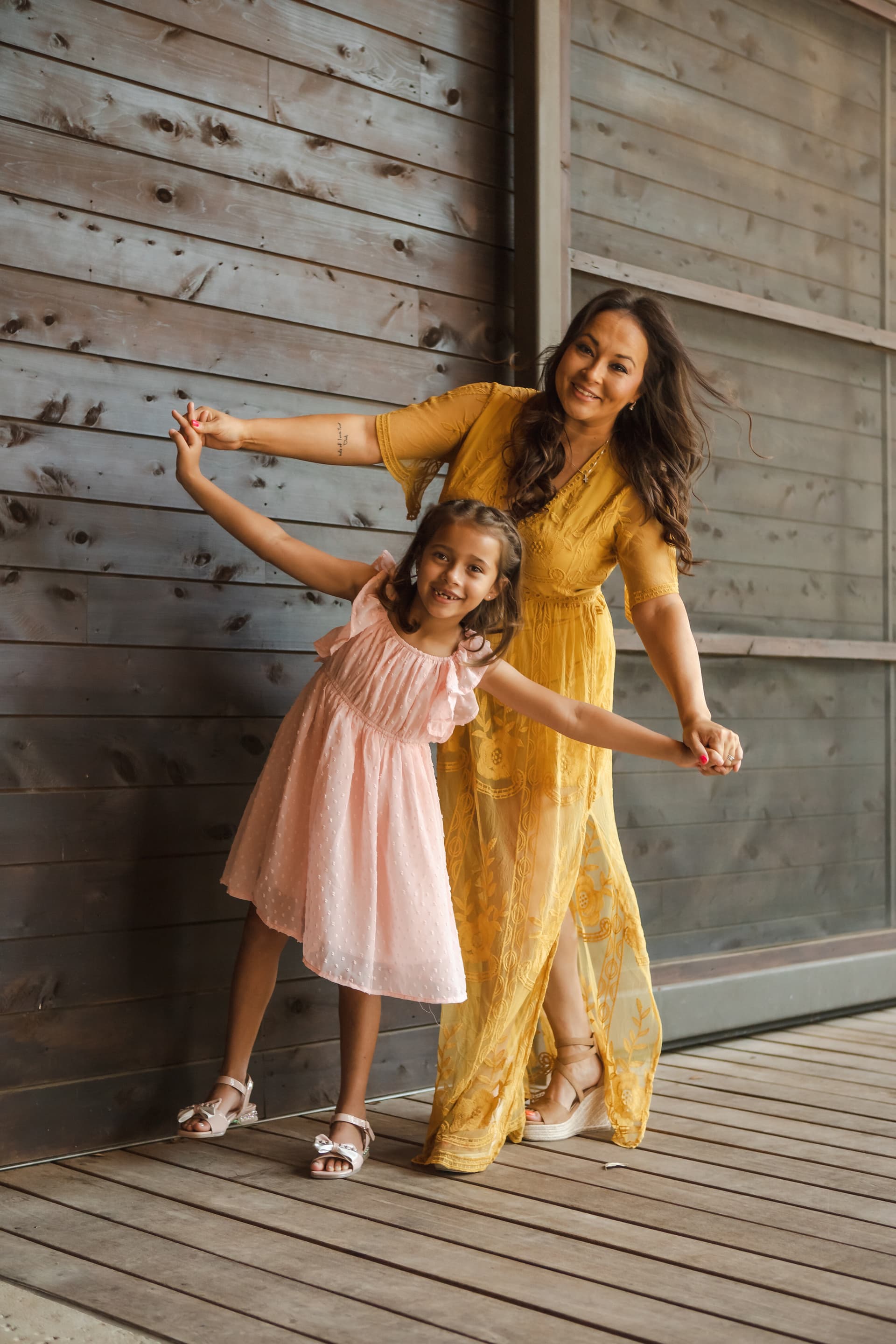 Mother and daughter posing playfully in front of a wooden wall