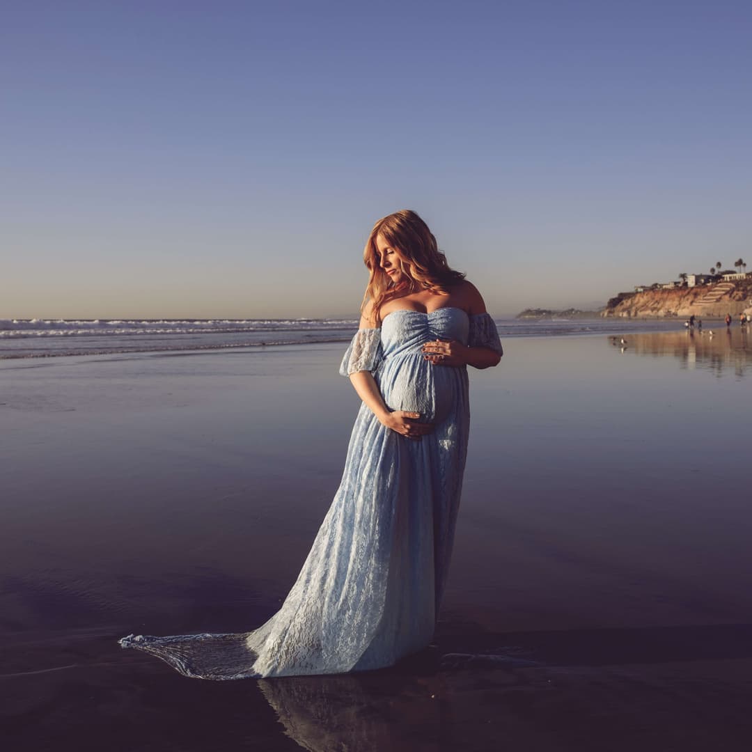 a pregnant woman on a beach in shallow water