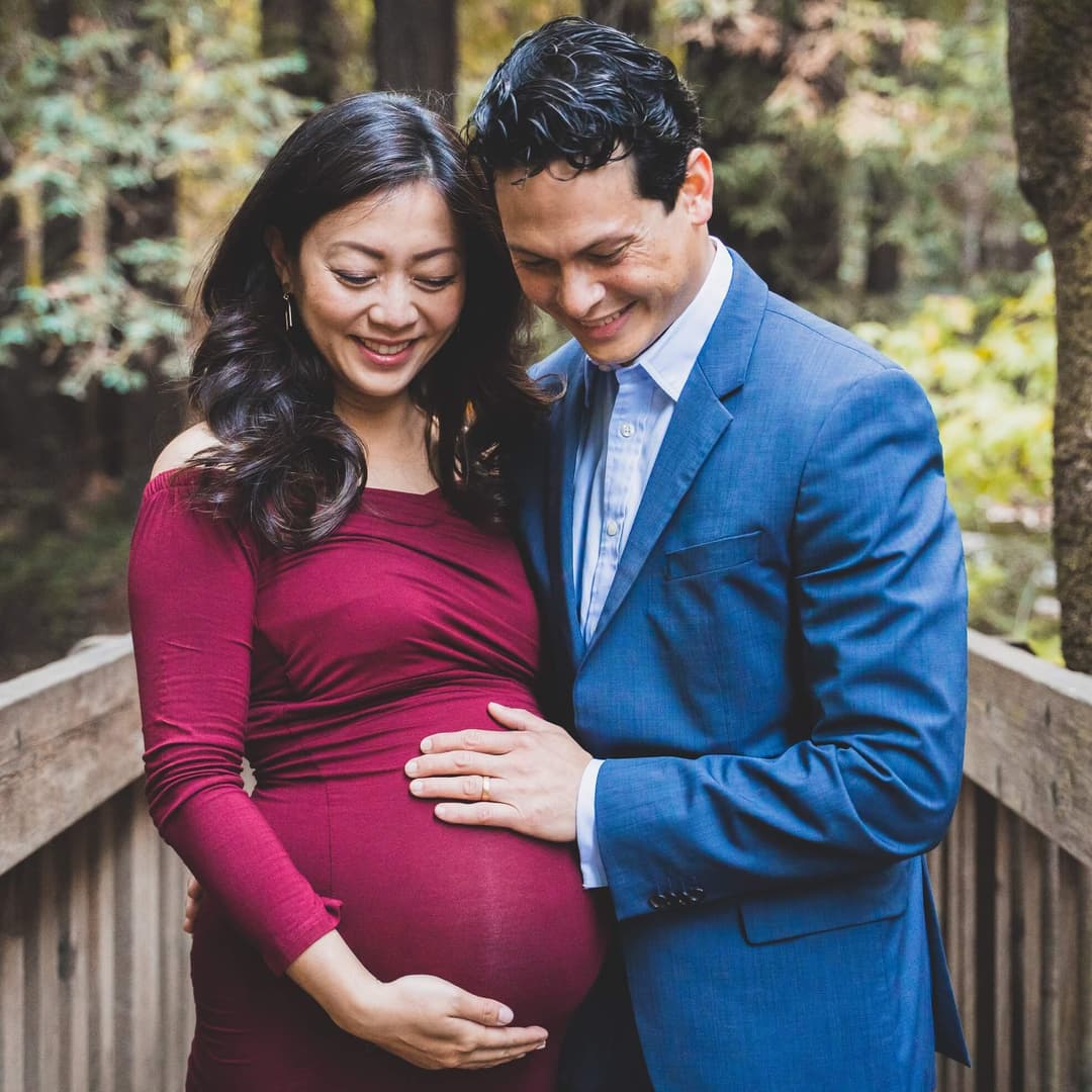 pregnant woman and her husband on a bridge in a forest