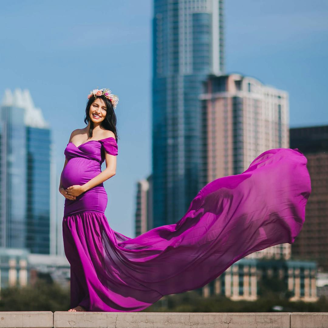 pregnant woman in a flowing dress in front of skyscrapers