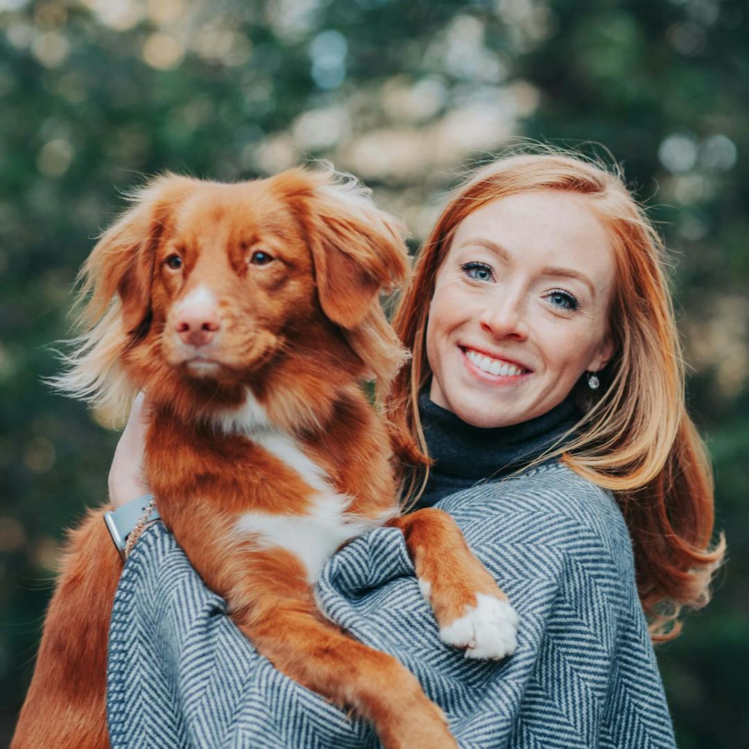 smiling woman holding up her pet dog