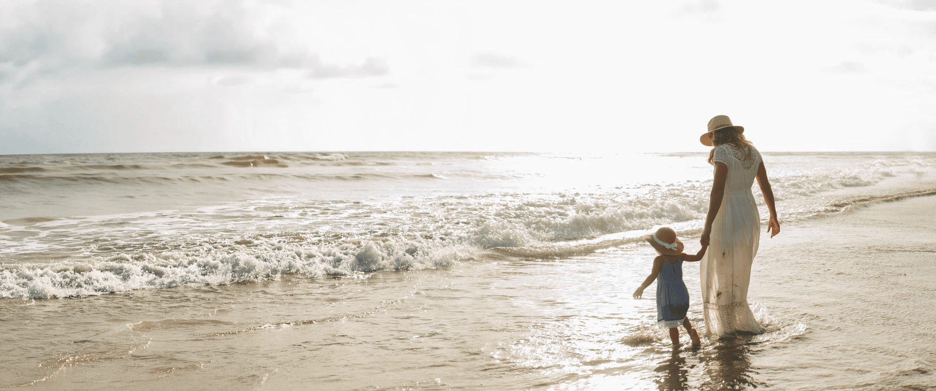 Mother and child walking together on a beach at sunset