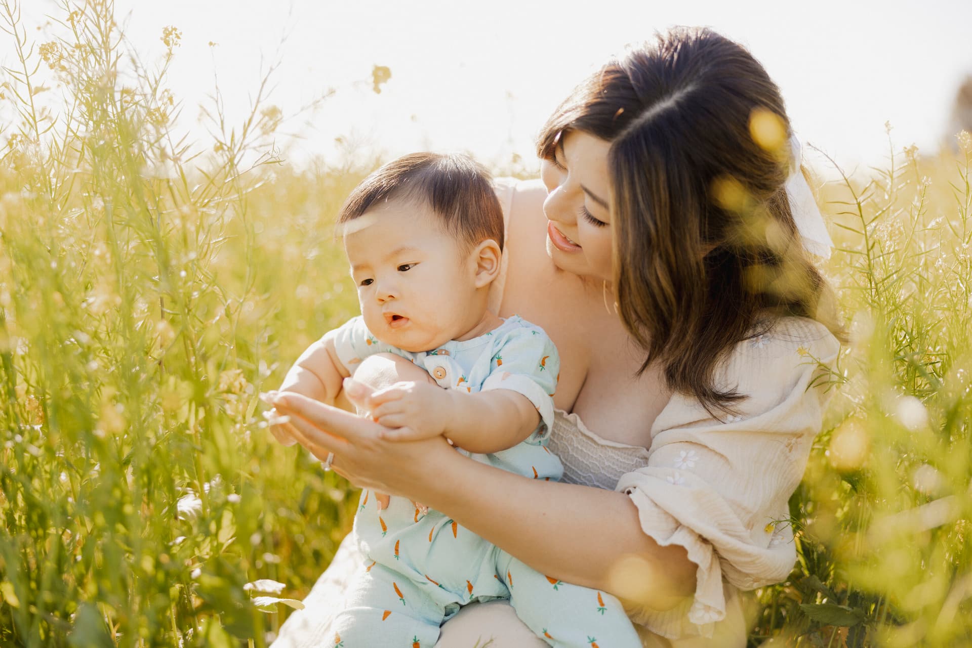 Mother holding her baby in a sunlit field