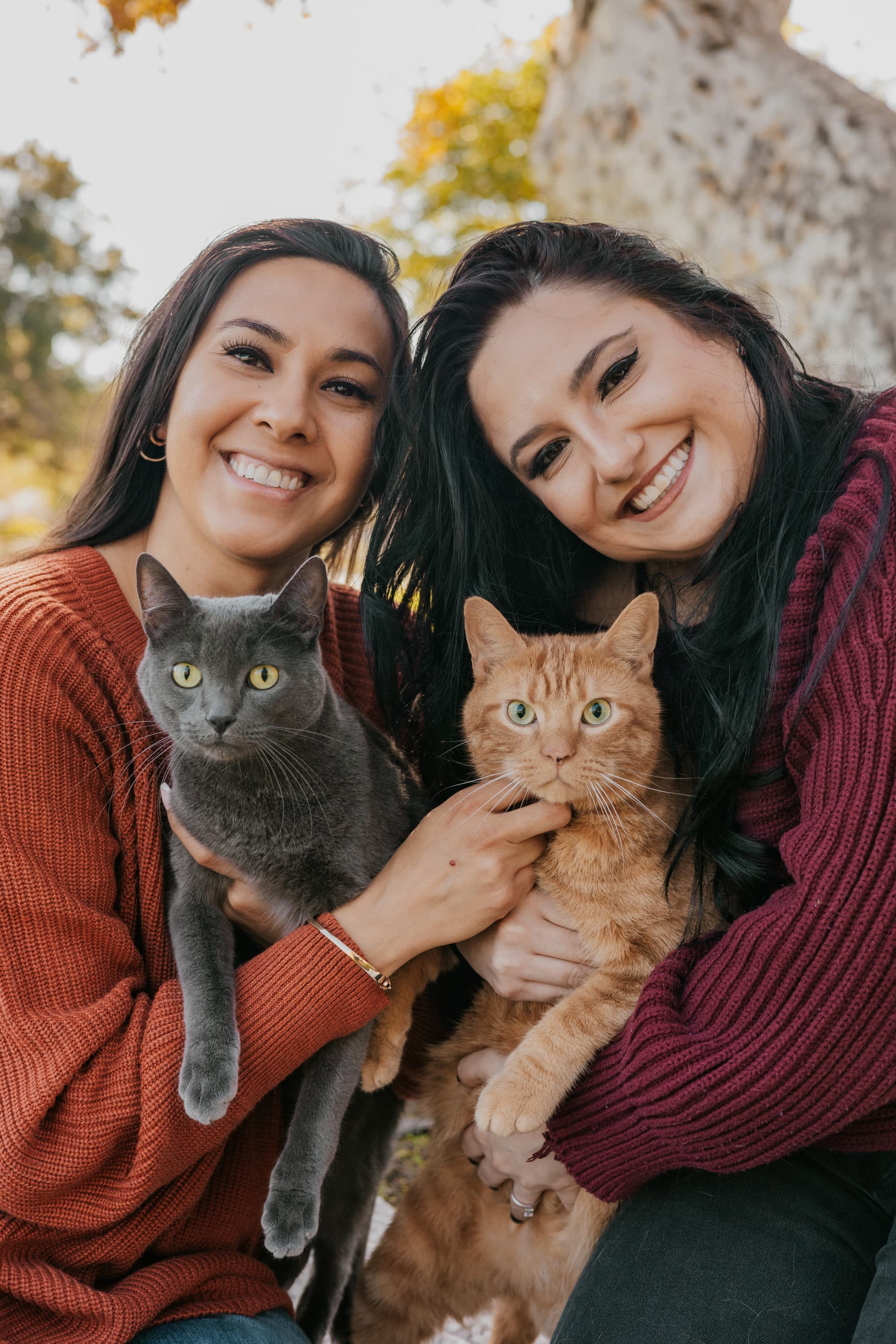 Two people smiling while holding their cats