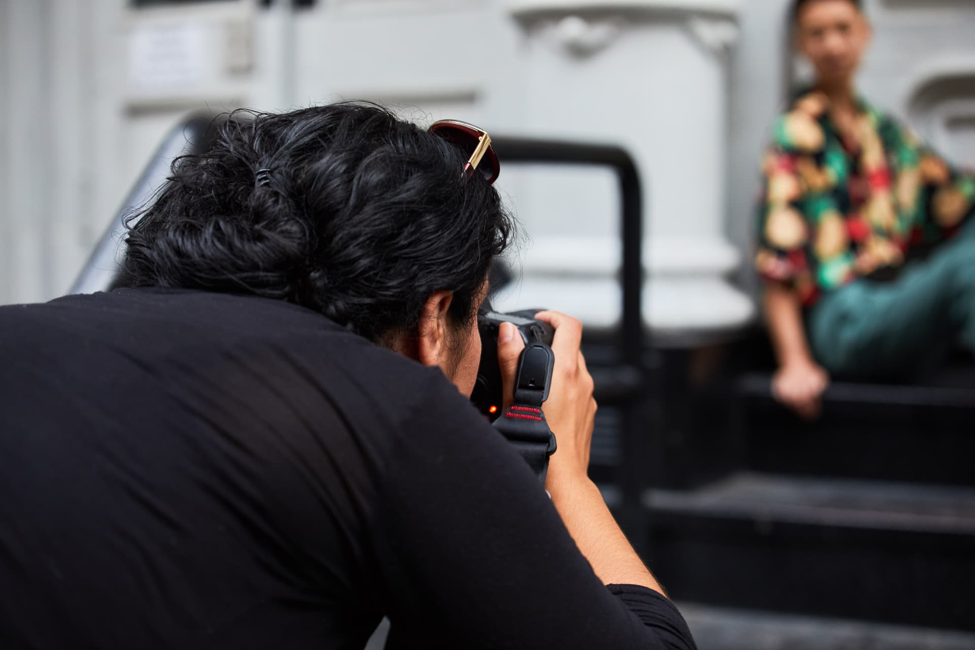 A photographer taking a picture of a person sitting on steps.