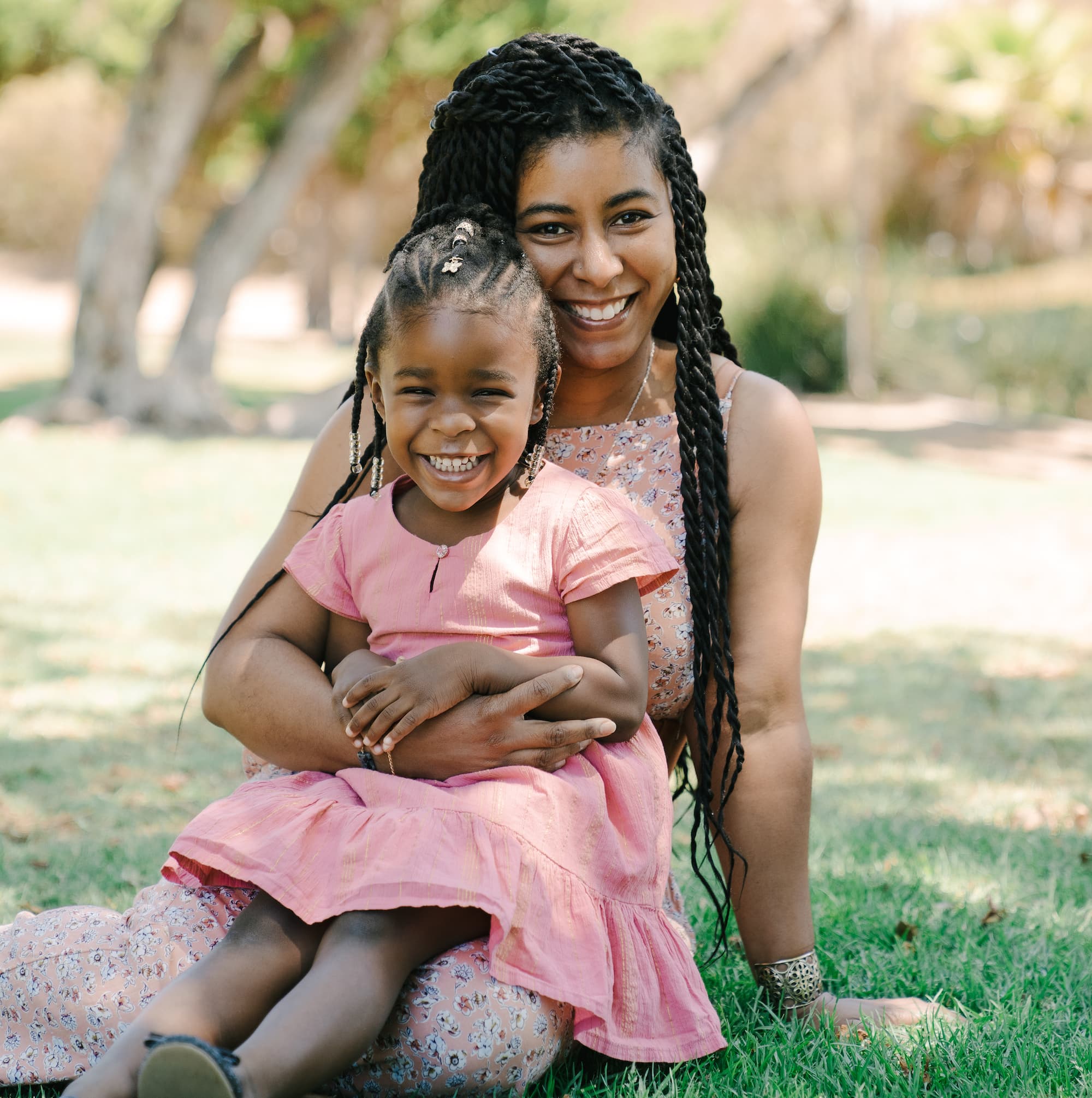 Mother and daughter smiling together in a park.