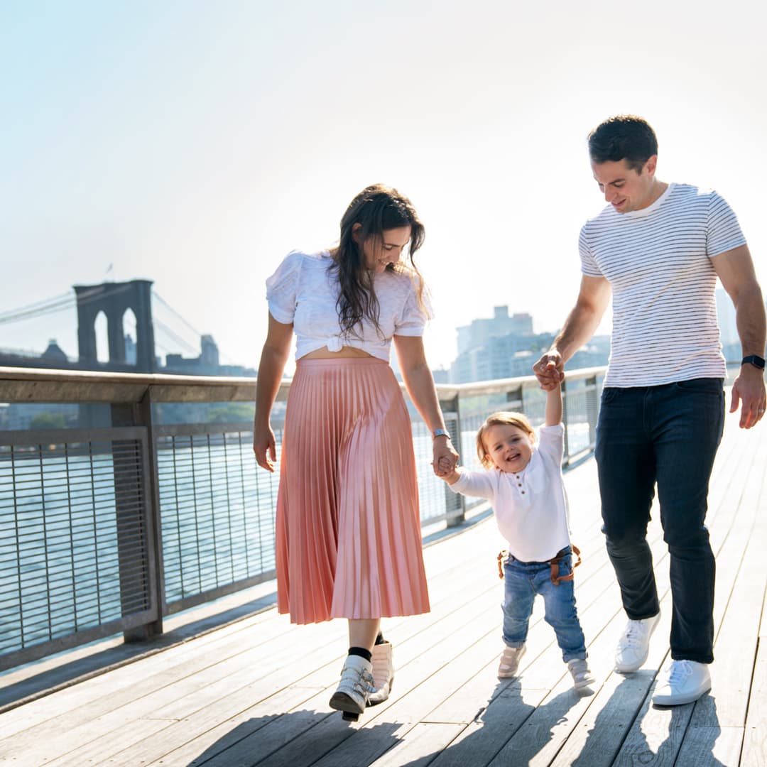 A young family holding hands and walking along a boardwalk