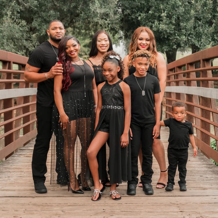 Family wearing matching outfits pose on a bridge for their free outdoor park photoshoot