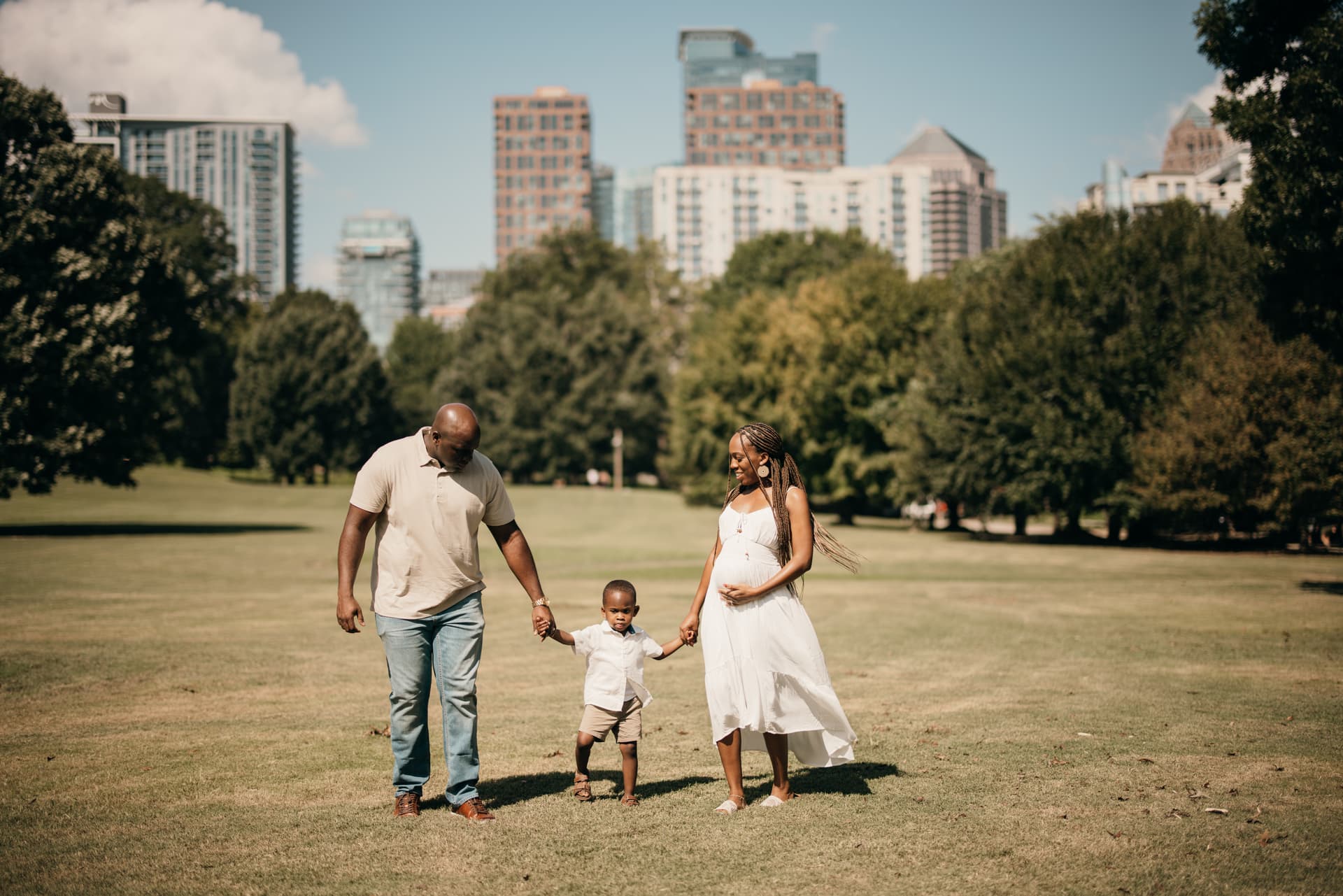 Family session at Piedmont Park with the Midtown Atlanta skyline behind them by a Shoott photographer.