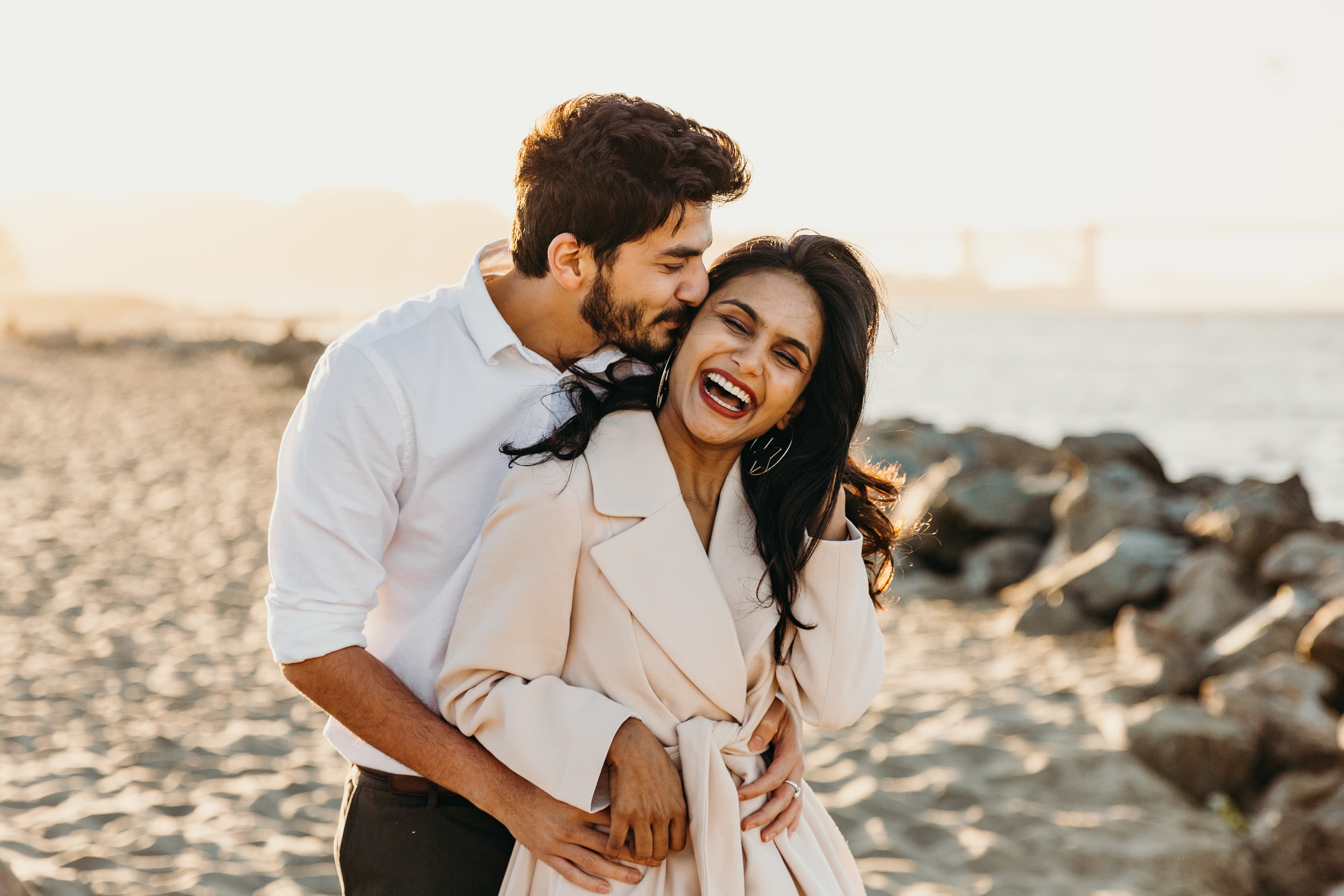 A happy couple embracing on the beach at sunset.