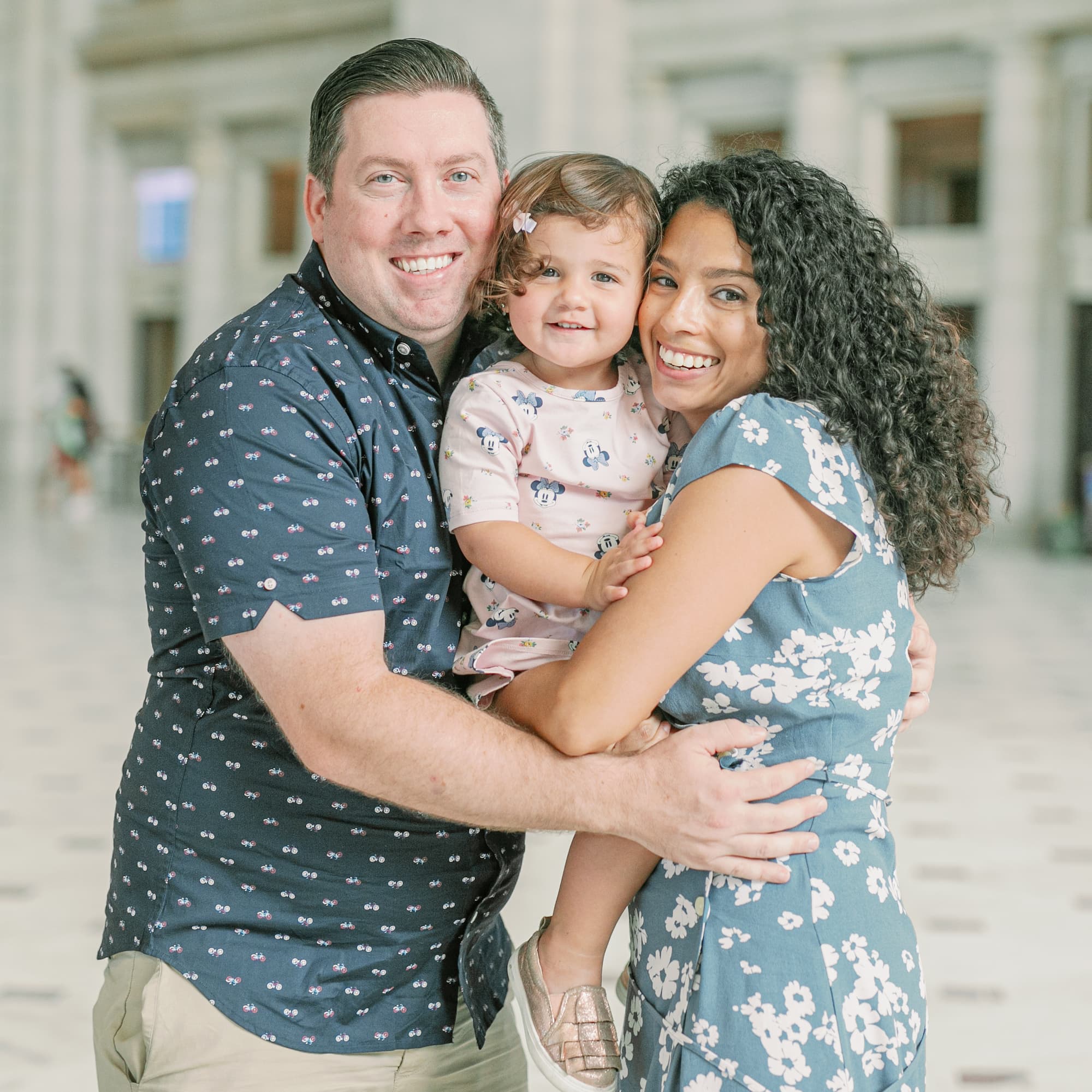 A smiling family with two adults and a young child posing together.