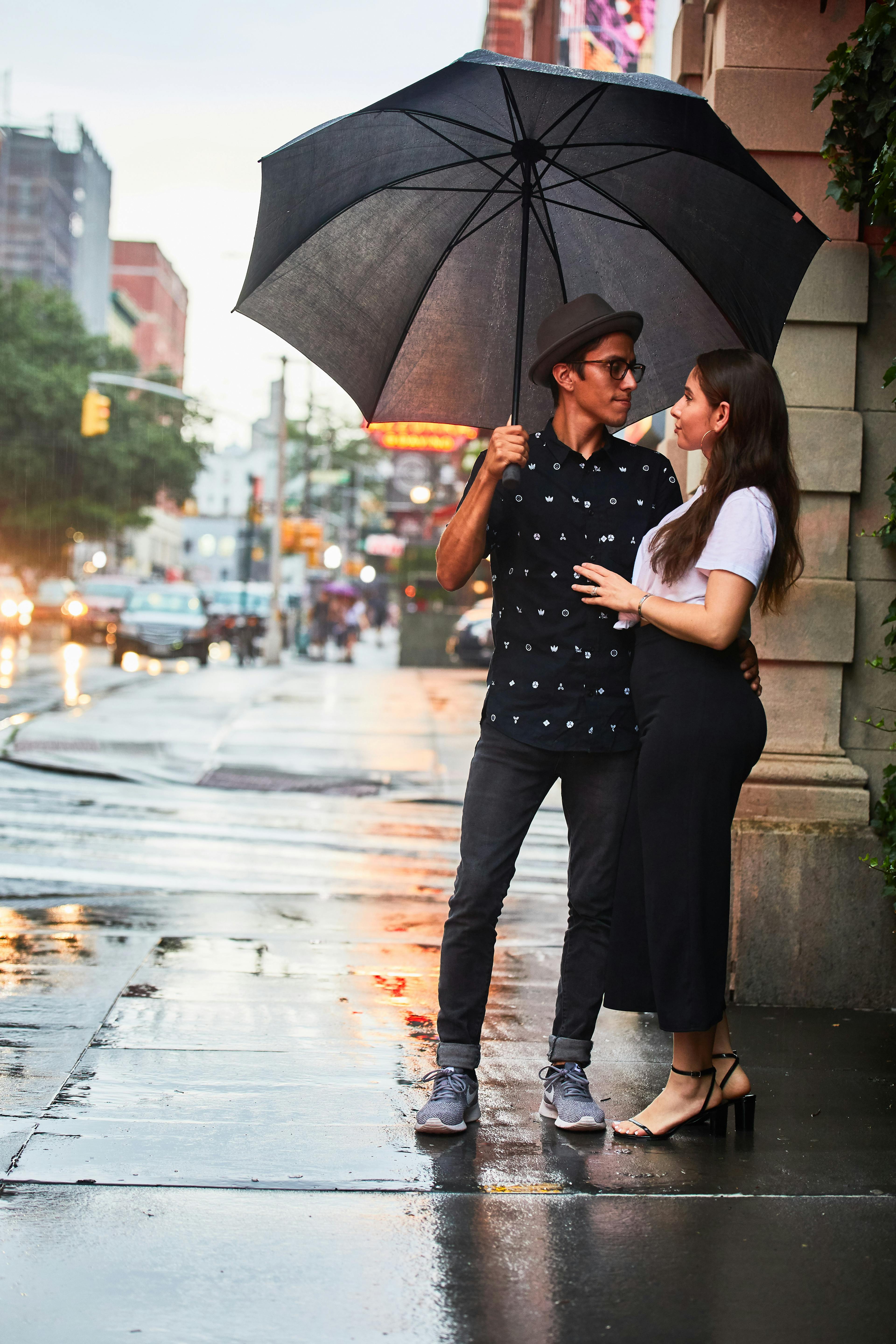 Couple standing under an umbrella on a rainy city street.