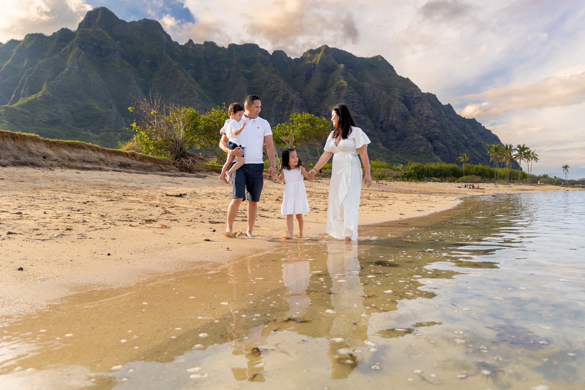 Asian family walking on beach in Kualoa Regional Park in O'ahu